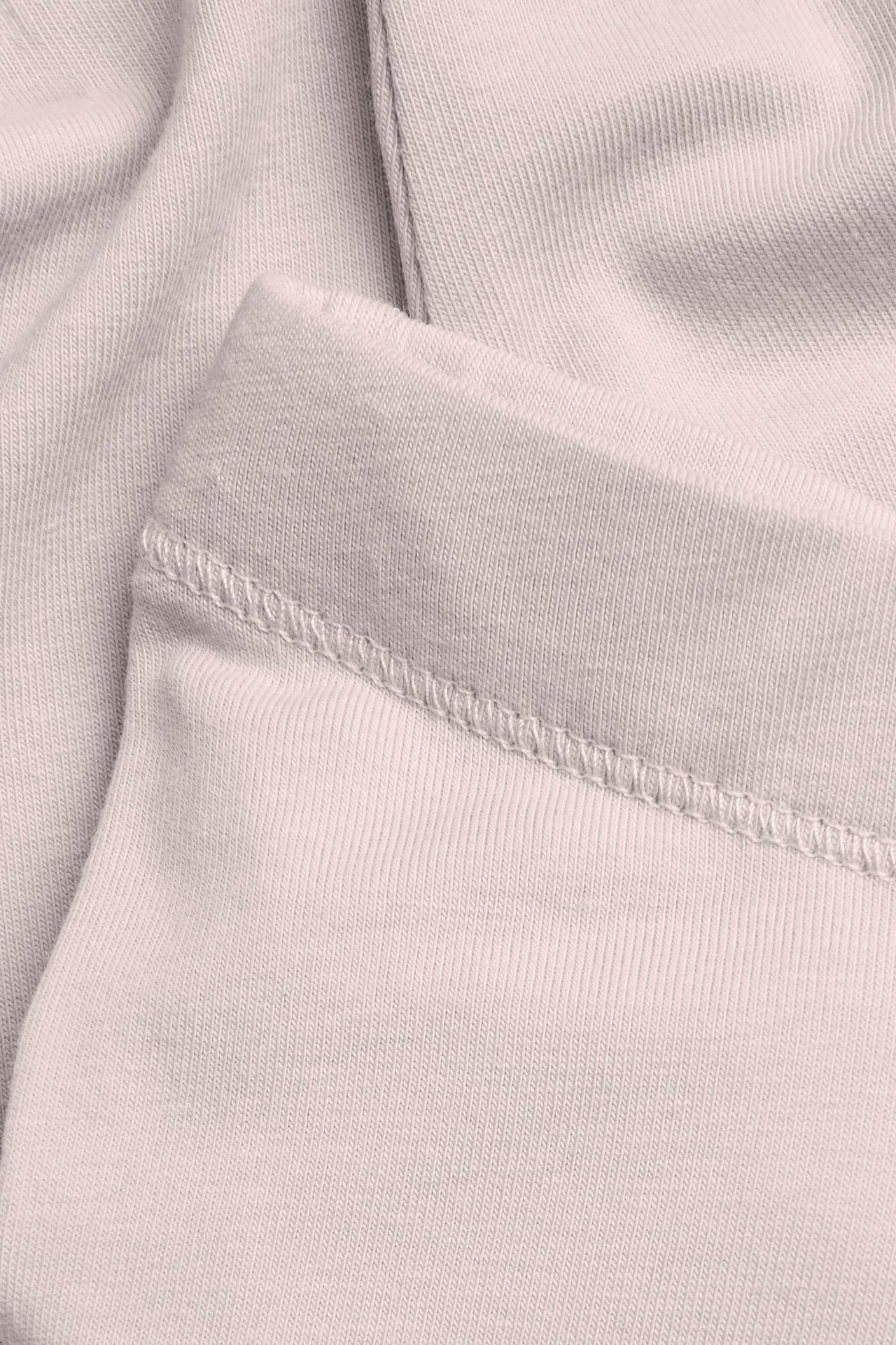 Nærbilde av lys beige ribbestrikket stoff med synlige sømmer.