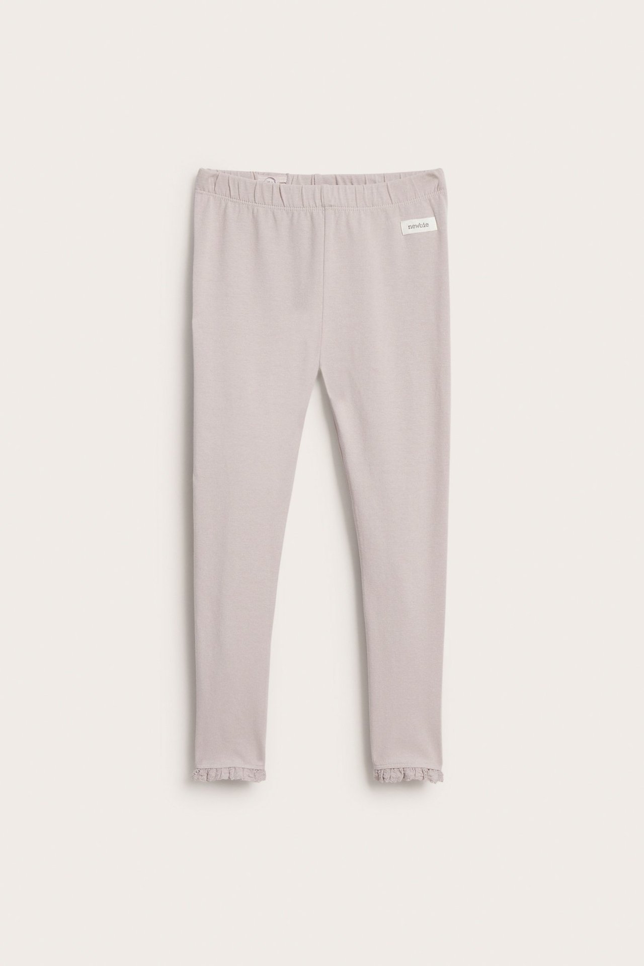 Widok z przodu: jasnoliliowe legginsy dżersejowe z elastycznym pasem i koronkowymi falbankami.