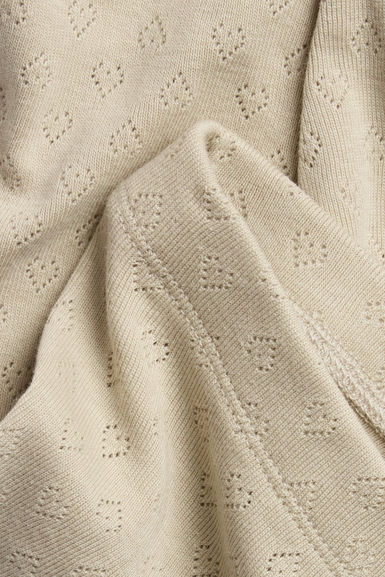 Zbliżenie beżowych bawełnianych legginsów pointelle z wzorem serc.