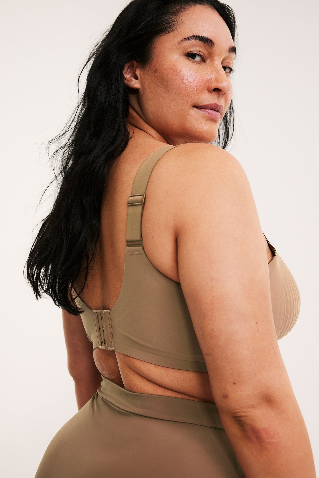 Widok z tyłu kobiety w brązowym biustonoszu bez fiszbin, z mikrofibry, z prążkowanymi miseczkami i majtkami.