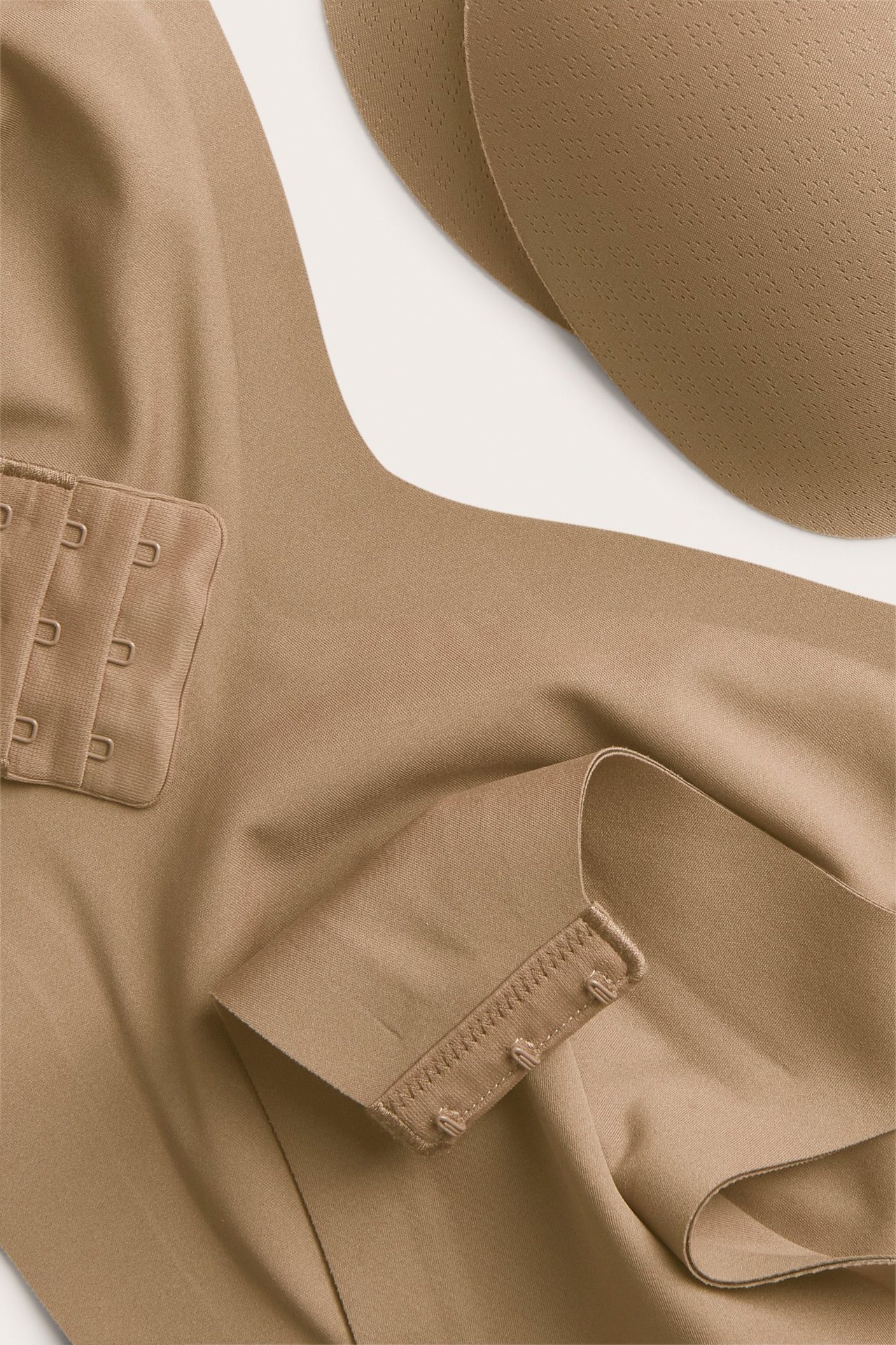 Zbliżenie na brązowy bezfiszbinowy biustonosz z mikrofibry, z trójrzędowym zapięciem na haftki i wyjmowanymi wkładkami.