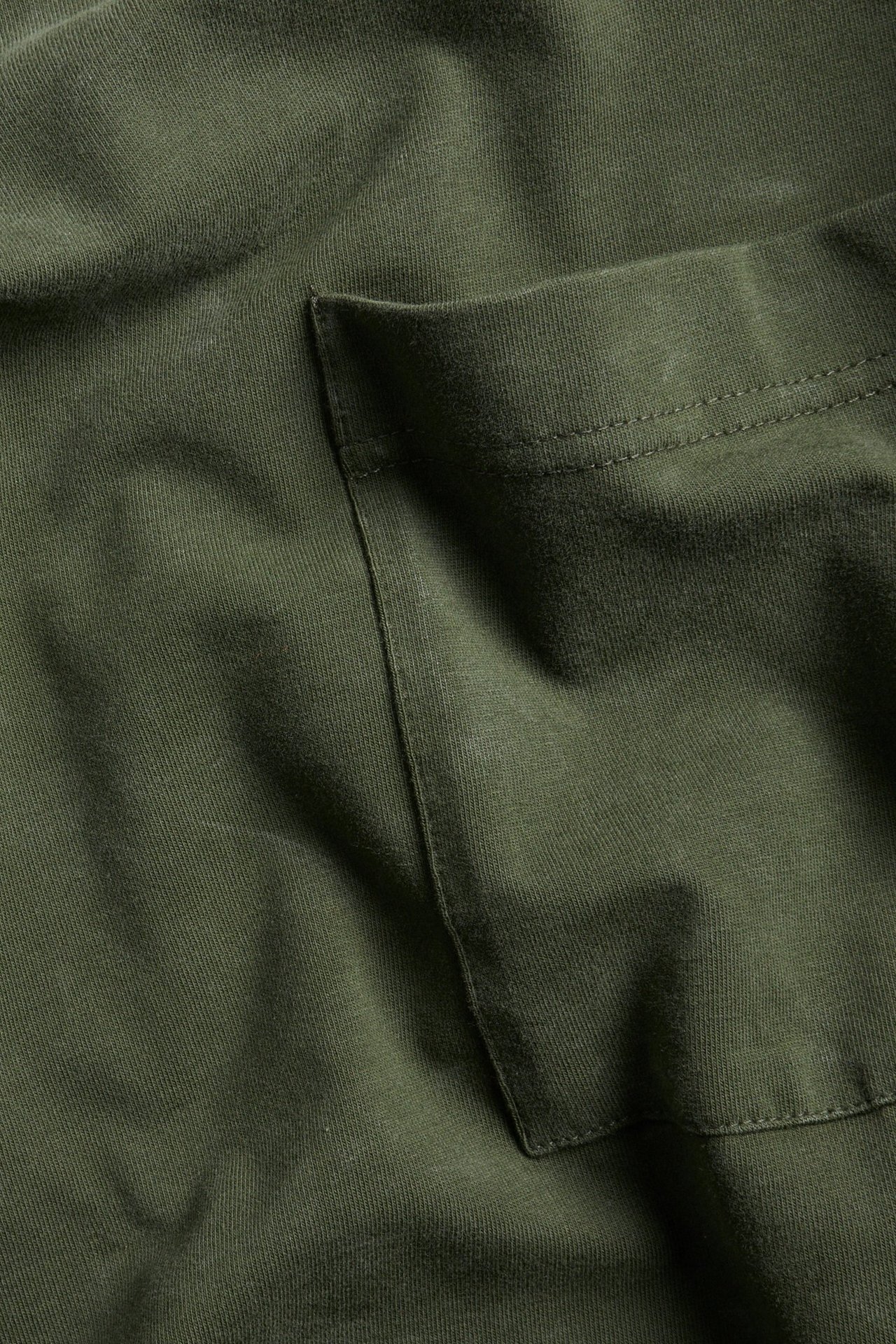 Zbliżenie na zielony melanżowy męski T-shirt z mieszanki bawełny z kieszenią na piersi i spraną powierzchnią.