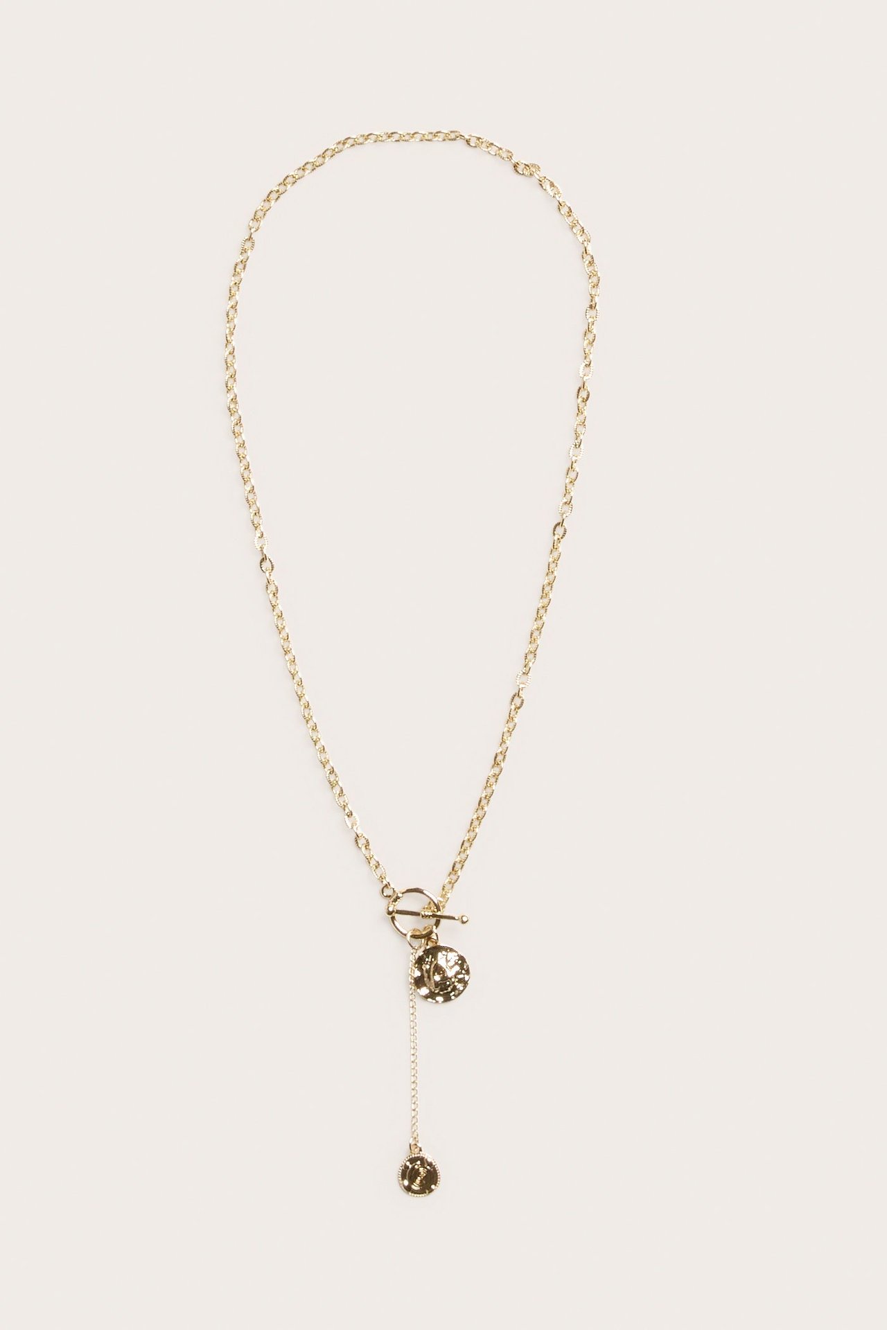 Frontvy av ett guldmetallhalsband med kedja, toggle-lås och två runda, texturerade myntberlocker.