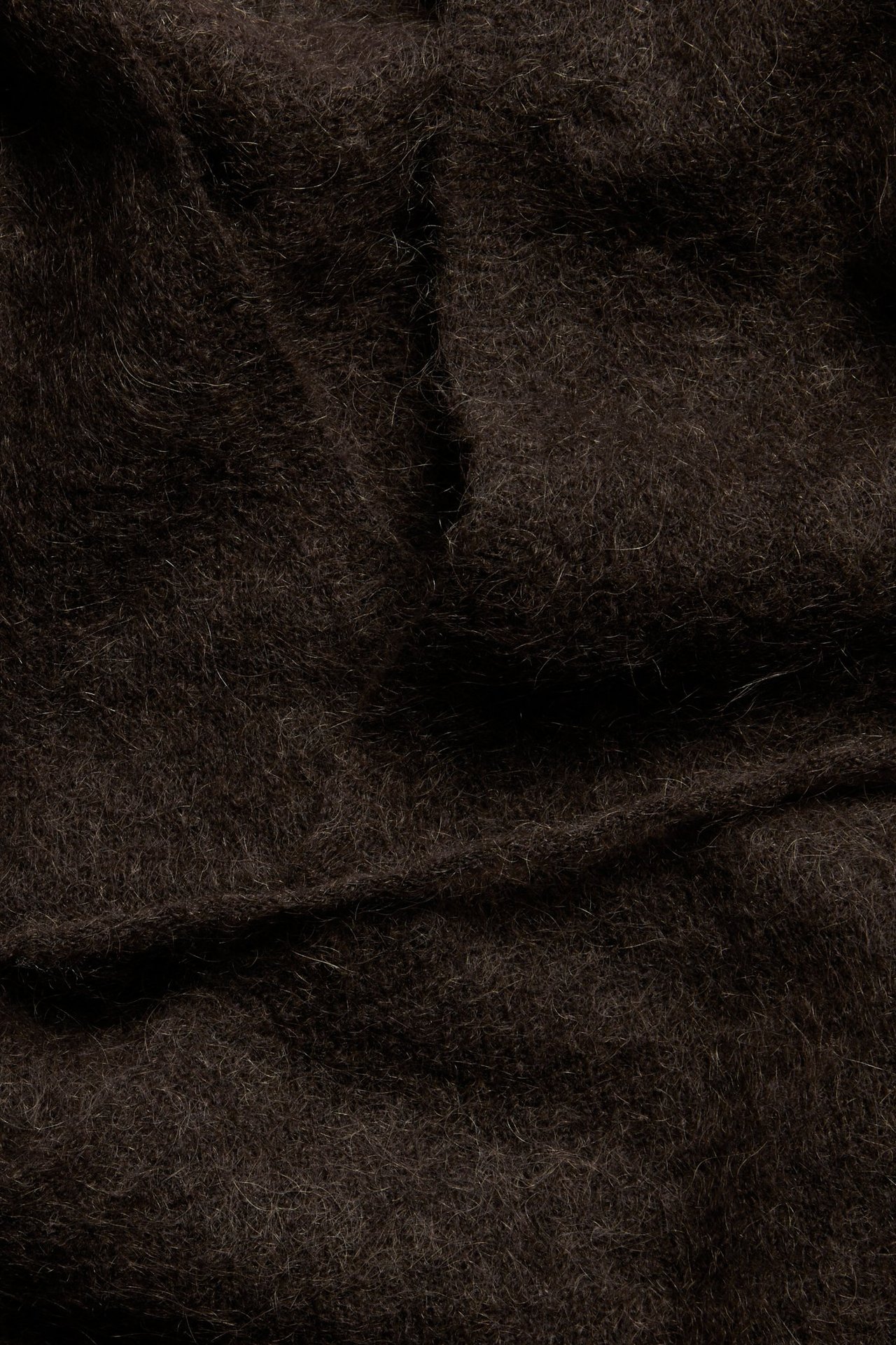 Zbliżenie na brązowy materiał kardiganu kopertowego z domieszką wełny, ukazujące jego miękką, puszystą fakturę.