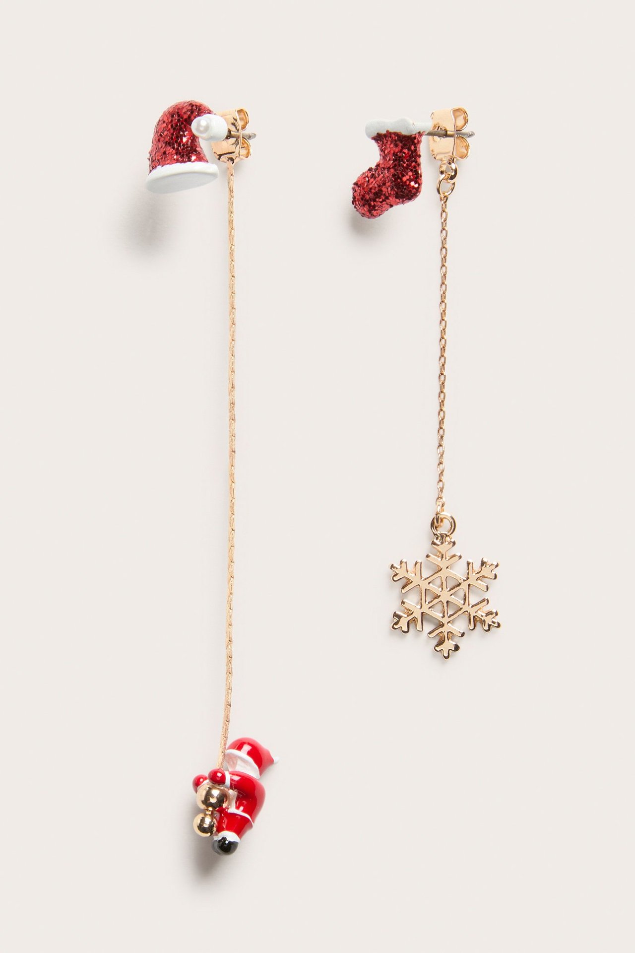 Närbild: Röda julörhängen med hängande tomtemössa, tomtefigur, julstrumpa och snöflinga.