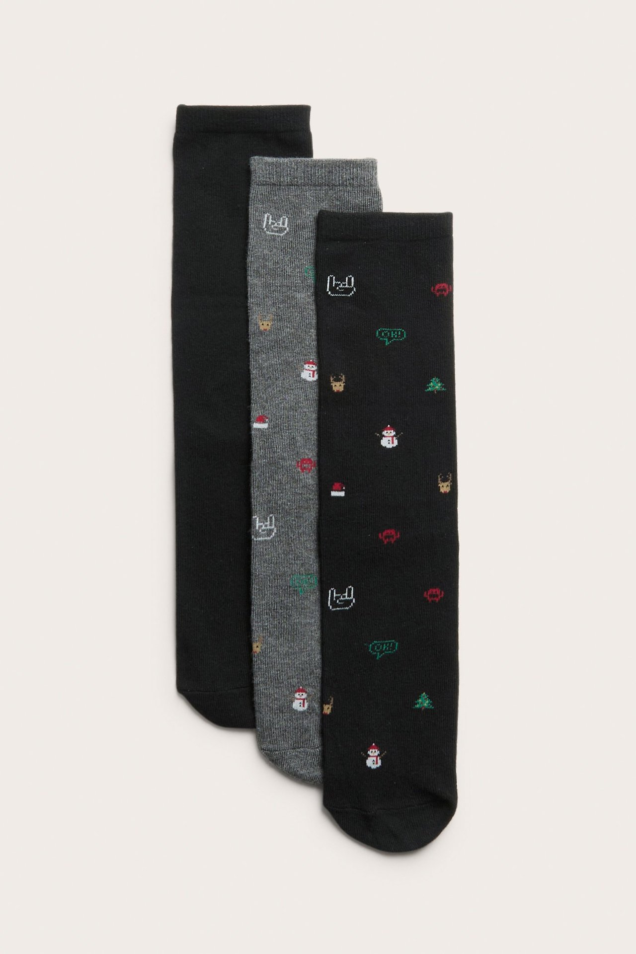 Lähikuva kolmen parin joulusukista lapsille: yhdet mustat, yhdet harmaat ja yhdet mustat jouluaiheiset.