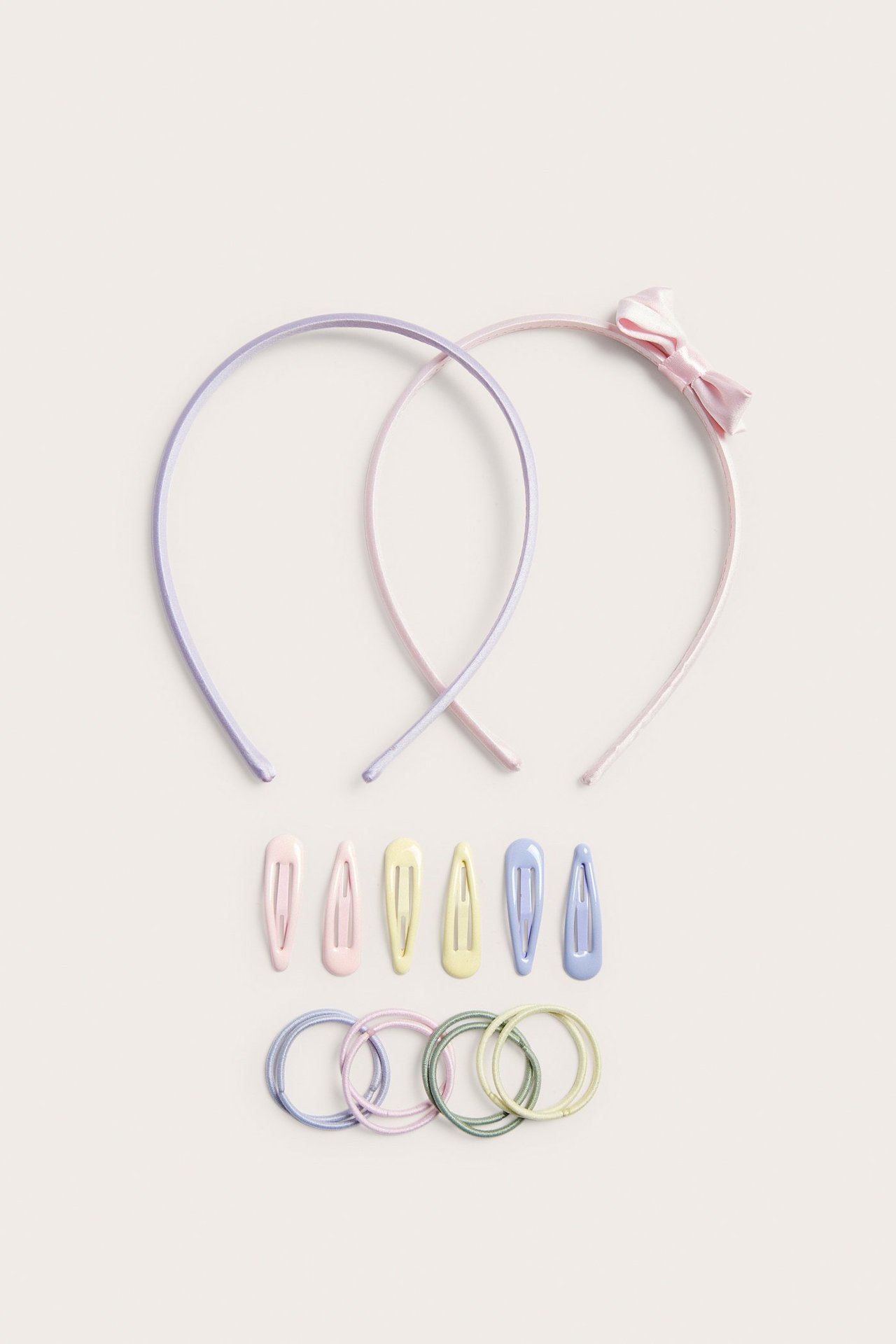 Widok z góry na pastelowe różowe, fioletowe opaski, różowe, żółte, niebieskie spinki i pasujące gumki.