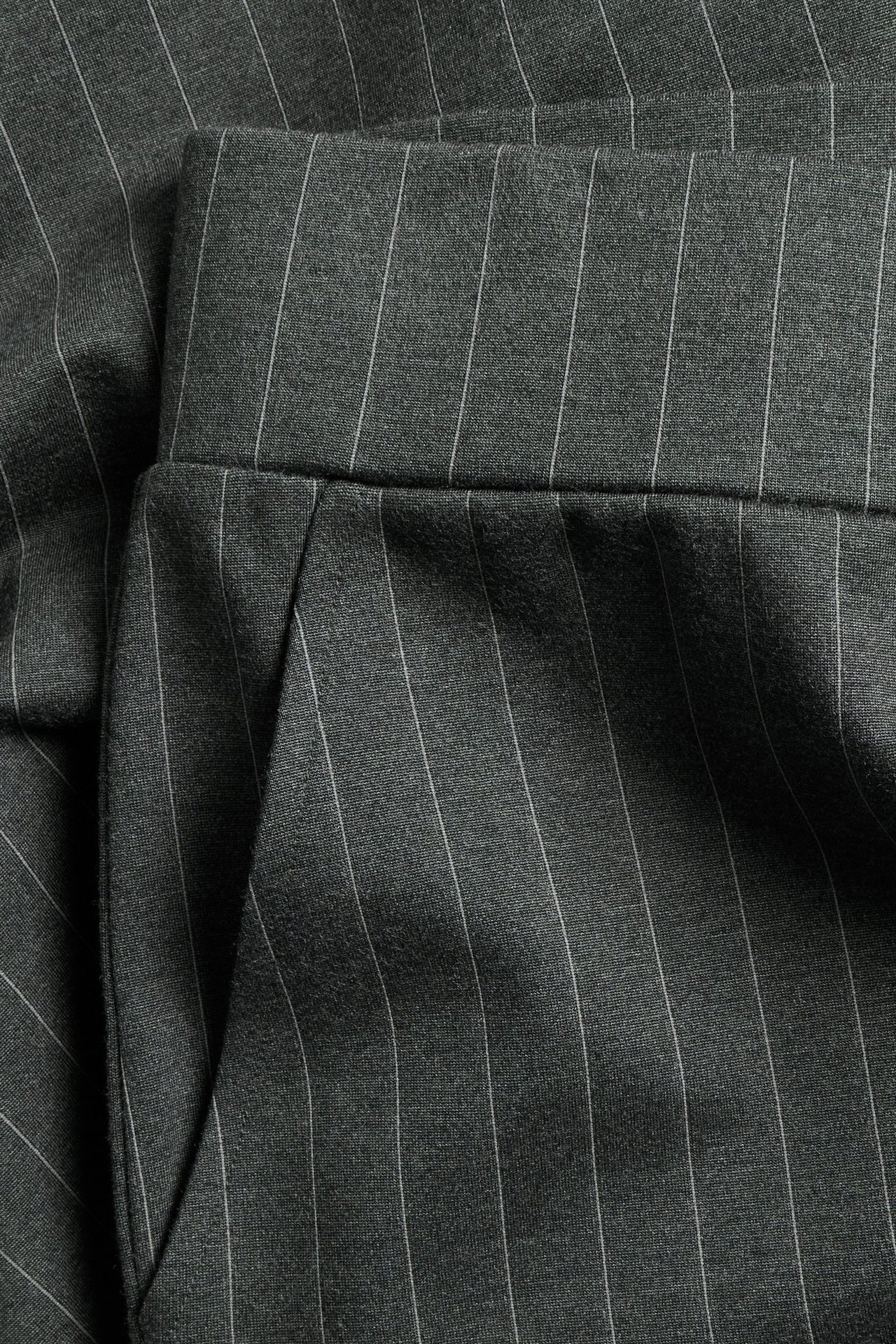 Zbliżenie na ciemnoszare, prążkowane spodnie dresowe z kieszenią i pasem.