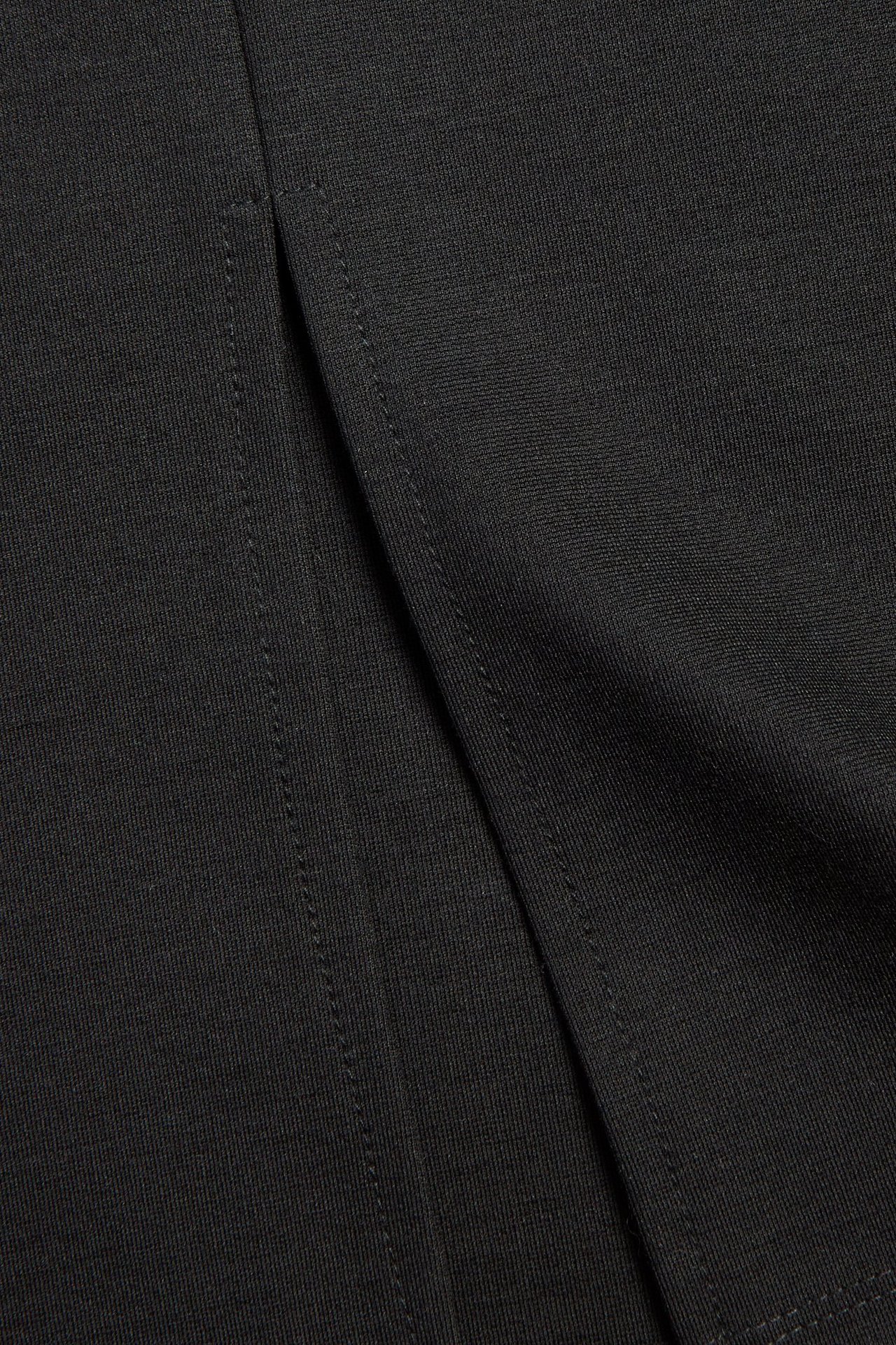 Zbliżenie czarnej ołówkowej spódnicy z dzianiny ponte roma z rozcięciem z tyłu.