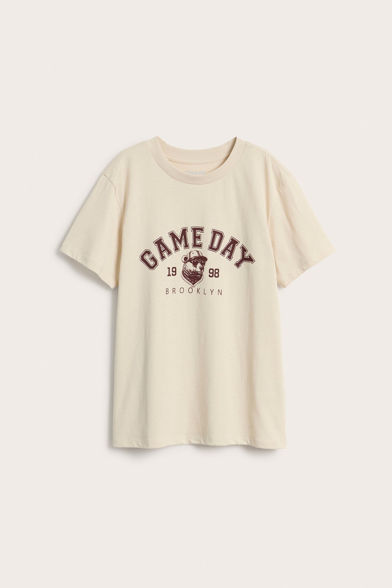 Framifrån, beige bomulls-t-shirt med mörkrött "GAME DAY" tryck framtill.