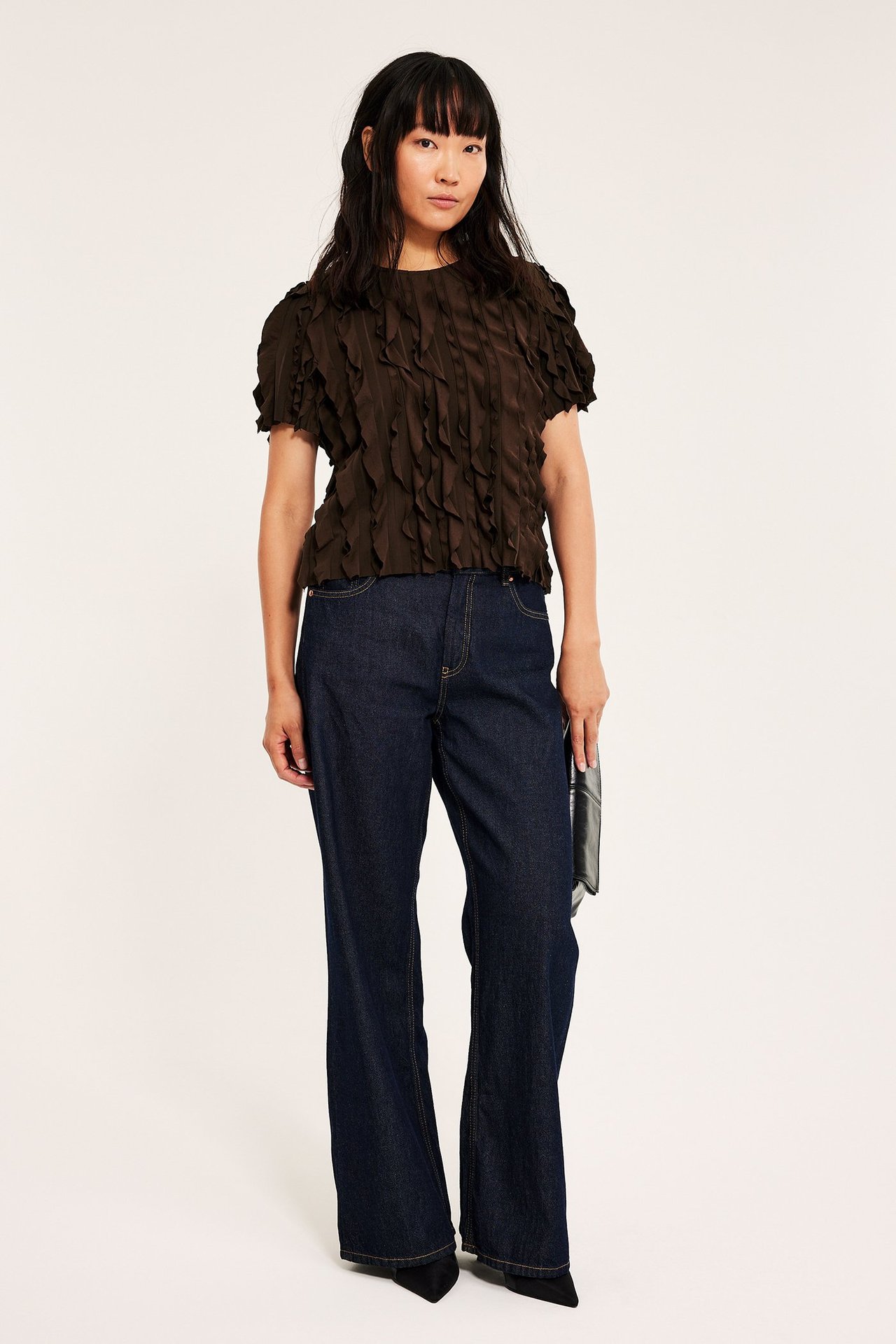 Tummanruskea boxy-toppi volanneilla, struktuurinen kangas, naisen päällä.