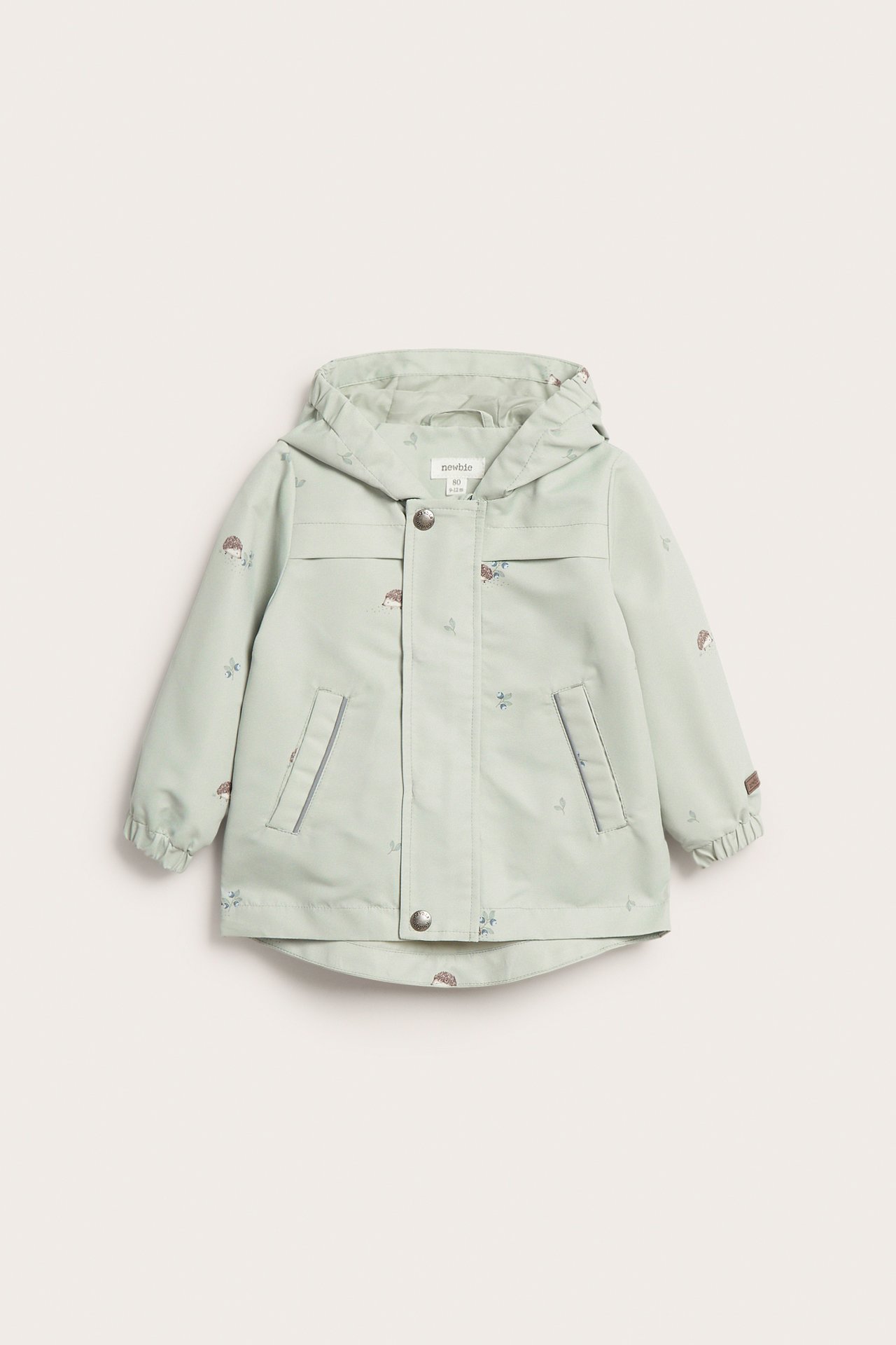 Frontvisning av en lys grønn barnejakke med hette, pinnsvinmønster, glidelås og trykknapper.