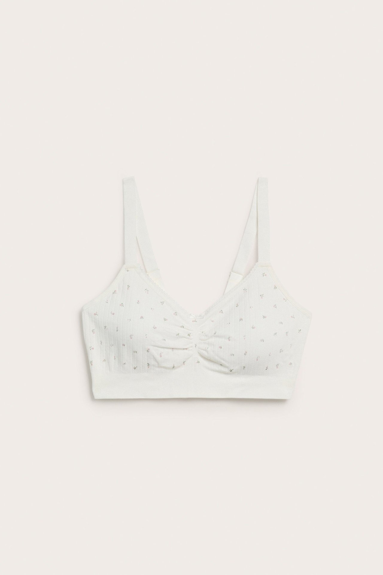 Edestä näkymä luonnonvalkoisista, saumattomista rintaliiveistä, joissa pointelle-kuvio ja rypytetty keskiosa.