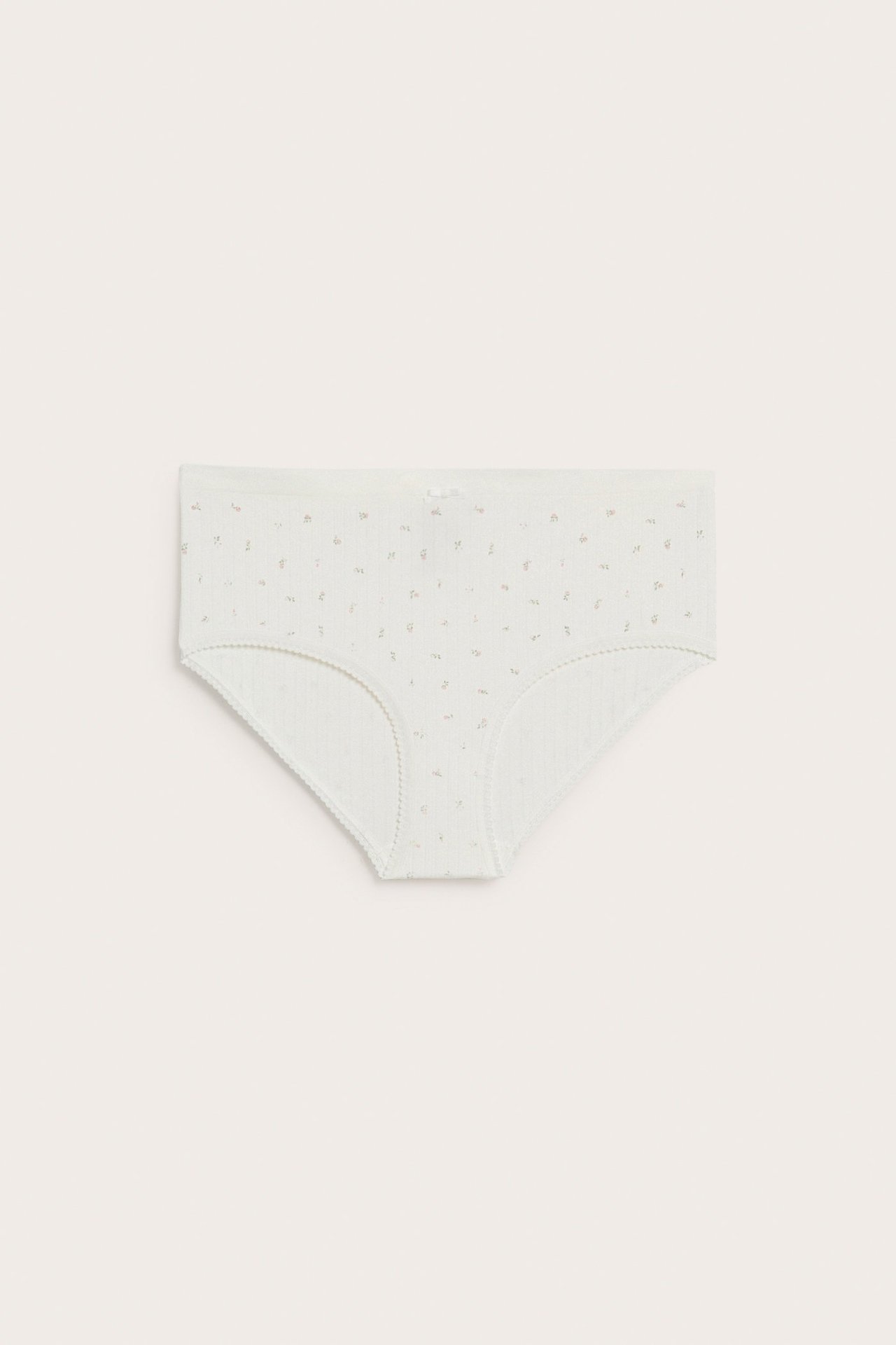 Frontvisning av offwhite sømløse hipster-truser med diskret blomstret pointelle-mønster og liten sløyfe.