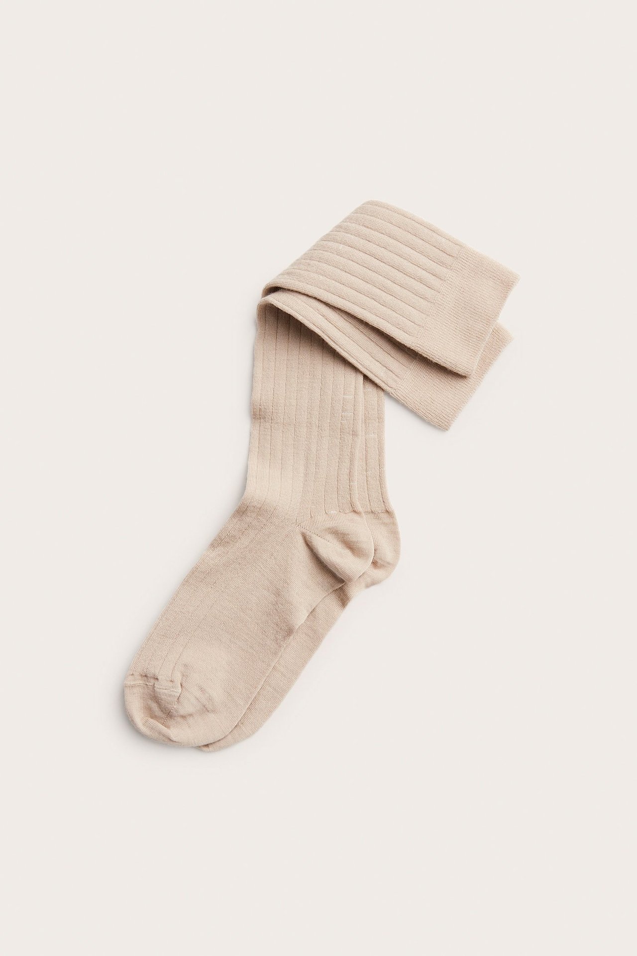 Toppvisning av en enkelt beige melert ribbestrikket knestrømpe i ullblanding, foldet.
