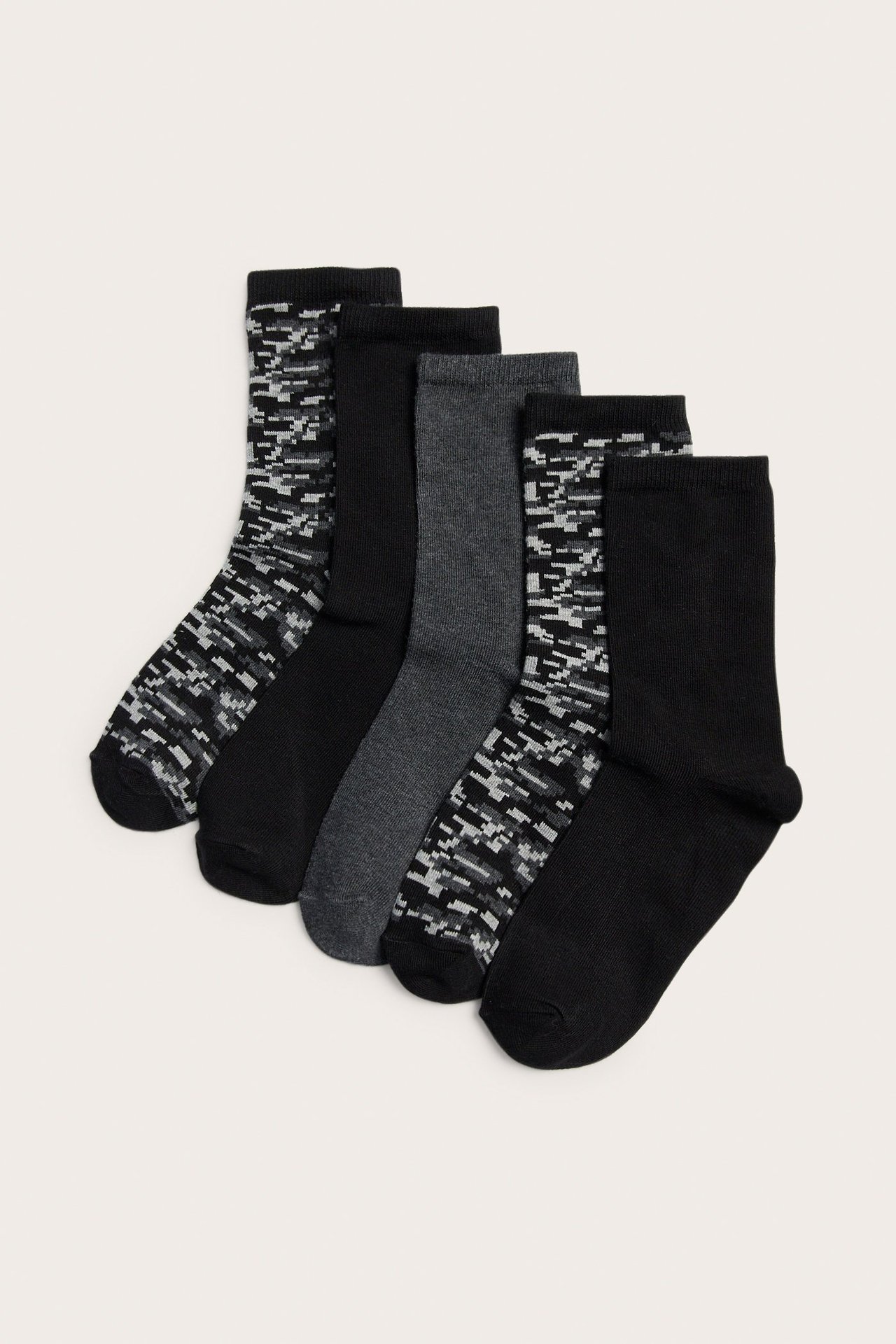 Ylhäältä kuvattu viisi paria lasten sukkia: kaksi mustaa, yksi tummanharmaa ja kaksi musta/harmaa maastokuvioista.