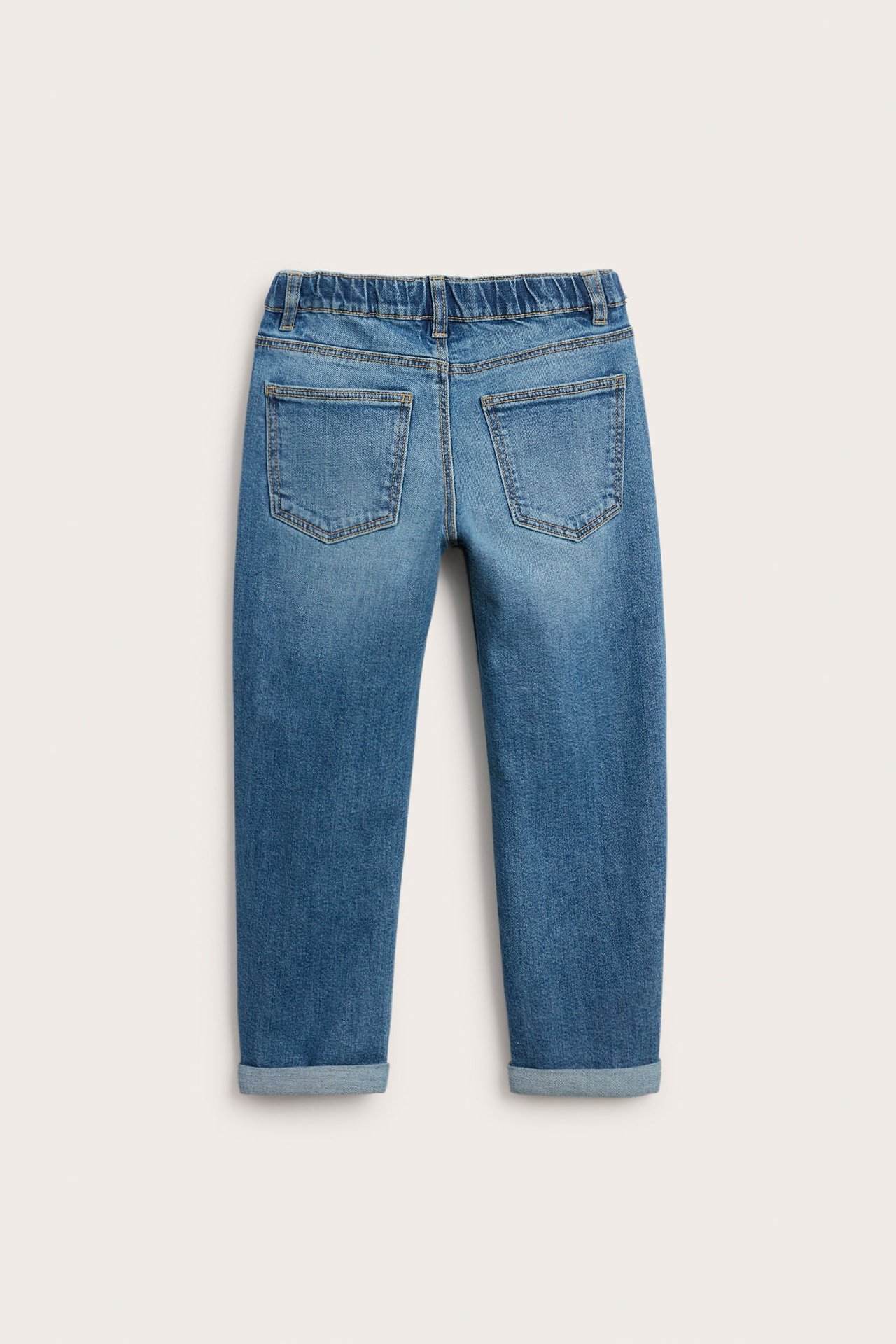 Bakfra av barnas blå denimjeans med elastisk linning og oppbrettede kanter.