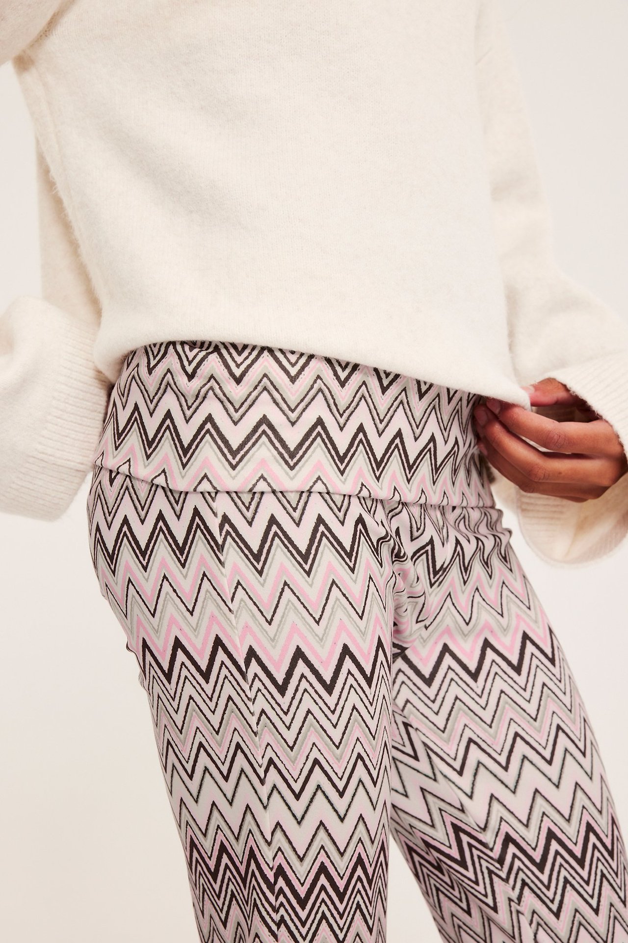 Framsida: barn i beiga sicksackmönstrade utsvängda yogabyxor och vit fluffig tröja.