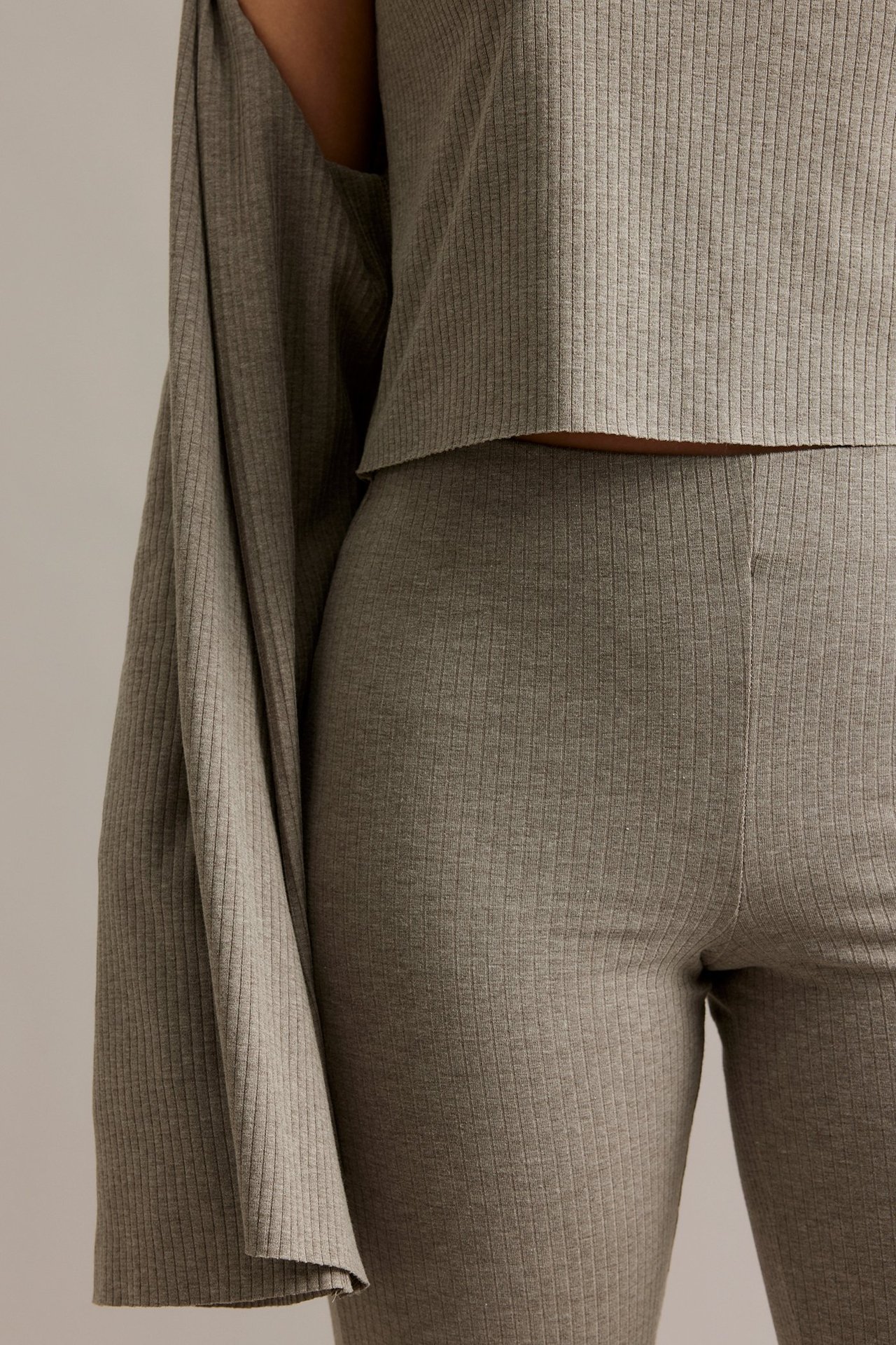 Zbliżenie na kobietę w melanżowych brązowych ryflowanych spodniach bootcut z elastycznym pasem i pasującym krótkim topie.