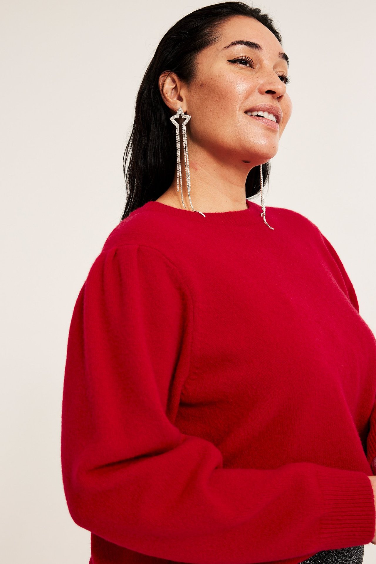 Röd stickad puffärmströja i enfärgad design, bärs av kvinna i profilbild.
