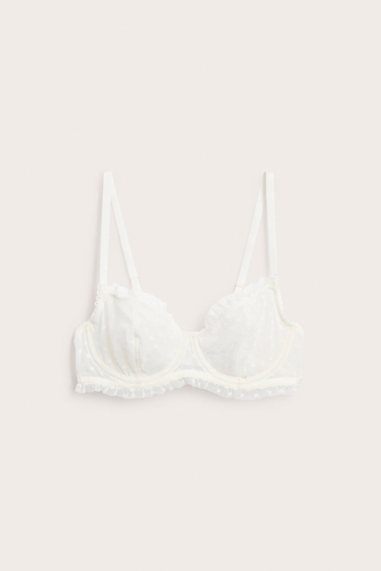 Frontbilde av en off-white, uvattert bøyle-BH med blondemønster av hjerter og volanger.