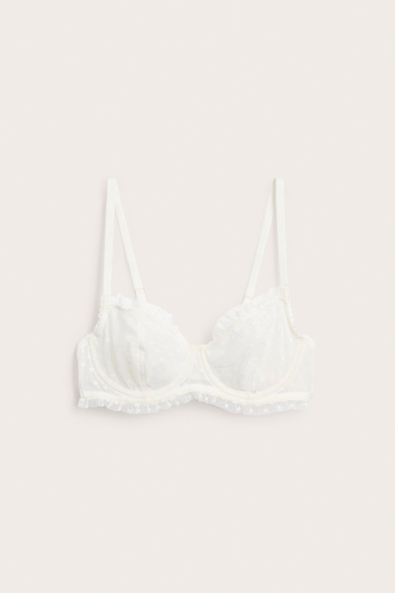 Widok z przodu: ecru biustonosz z fiszbinami, bez wypełnienia, koronkowy wzór serca, falbanki.