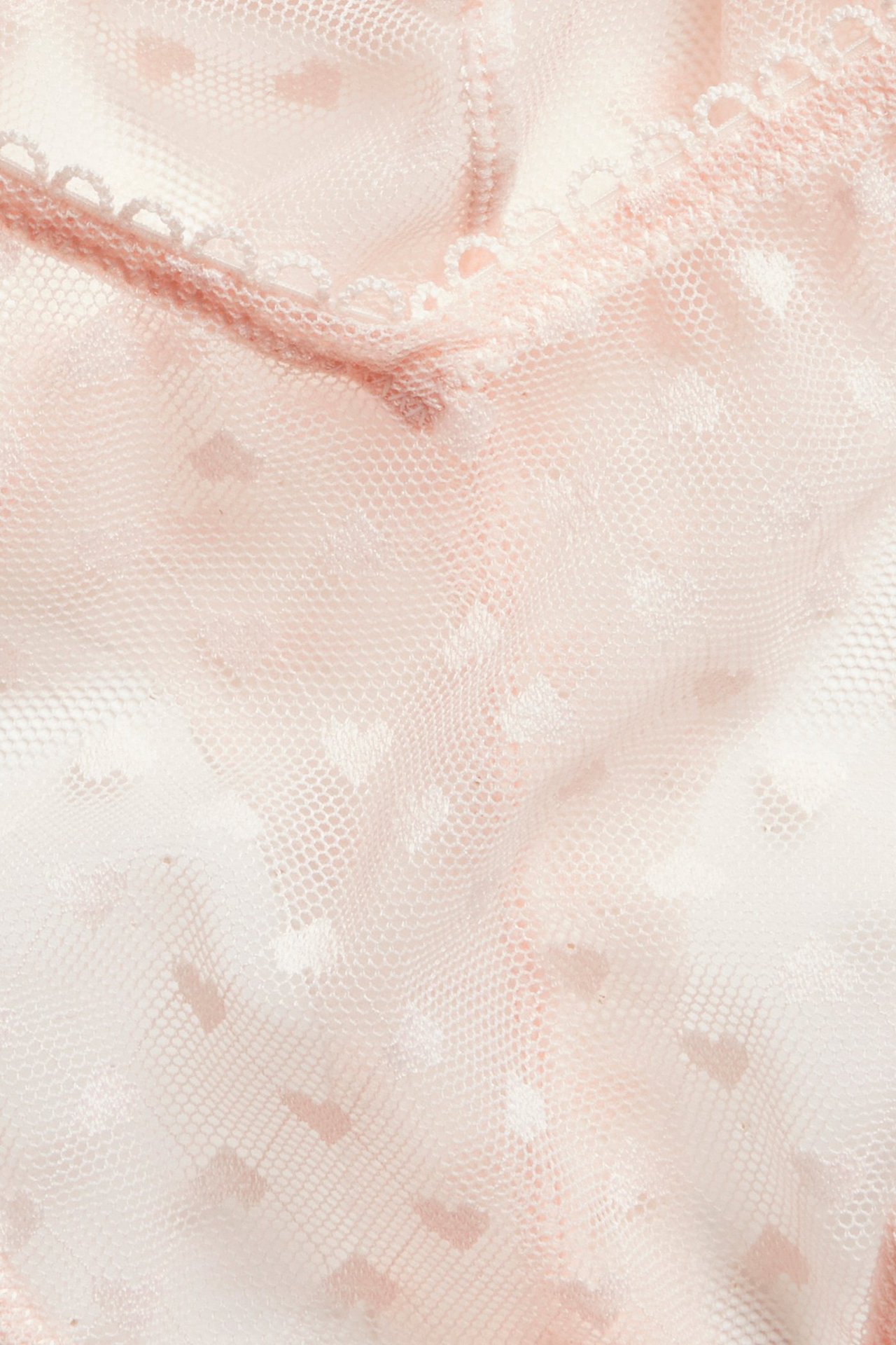 Lähikuva vaaleanpunaisista sydänkuvioisista pitsihalfstring-alushousuista ja pikoreunuksesta.