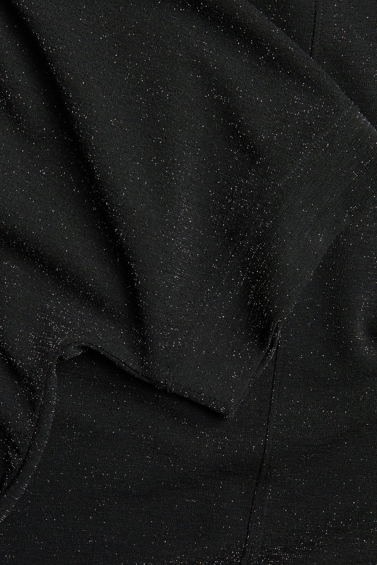 Widok z bliska czarnego krótkiego topu z lurexu z brokatem, o luźnym fasonie.