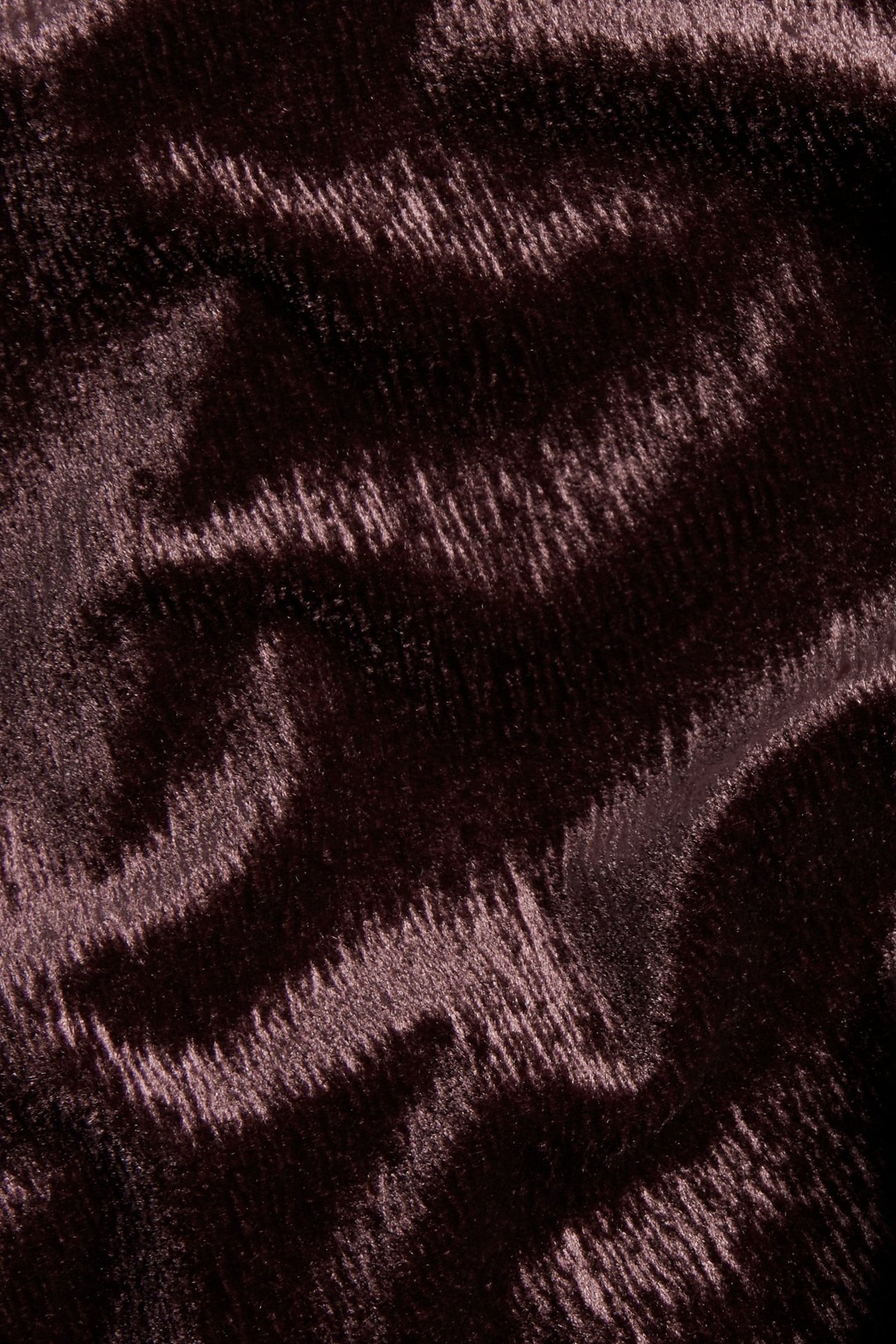 Zbliżenie na bordowy welurowy materiał o miękkiej, teksturowanej powierzchni.