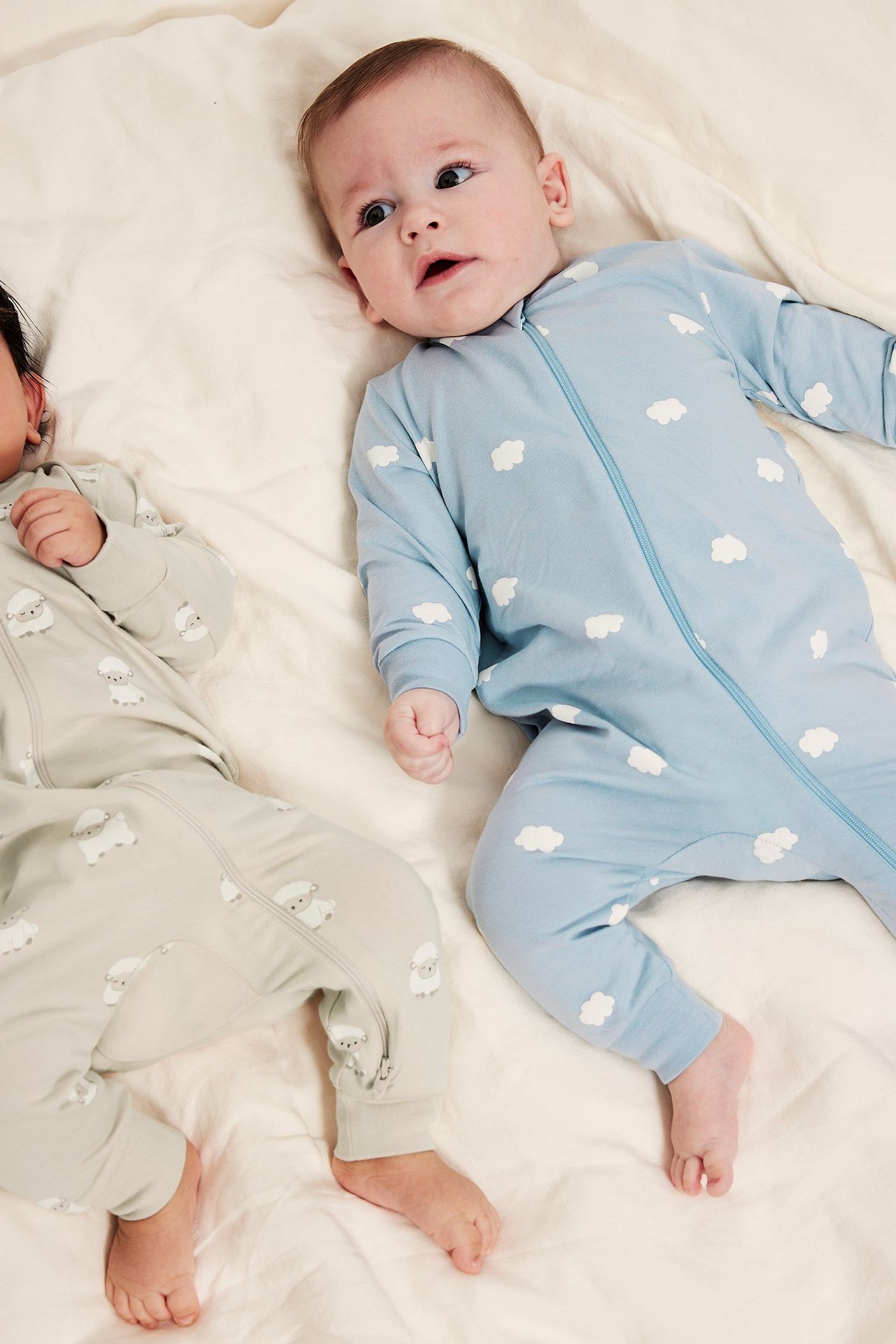 Kaksipakkaus vauvan pyjamaa, pilvitrik in beigen ja applikaatio takana.