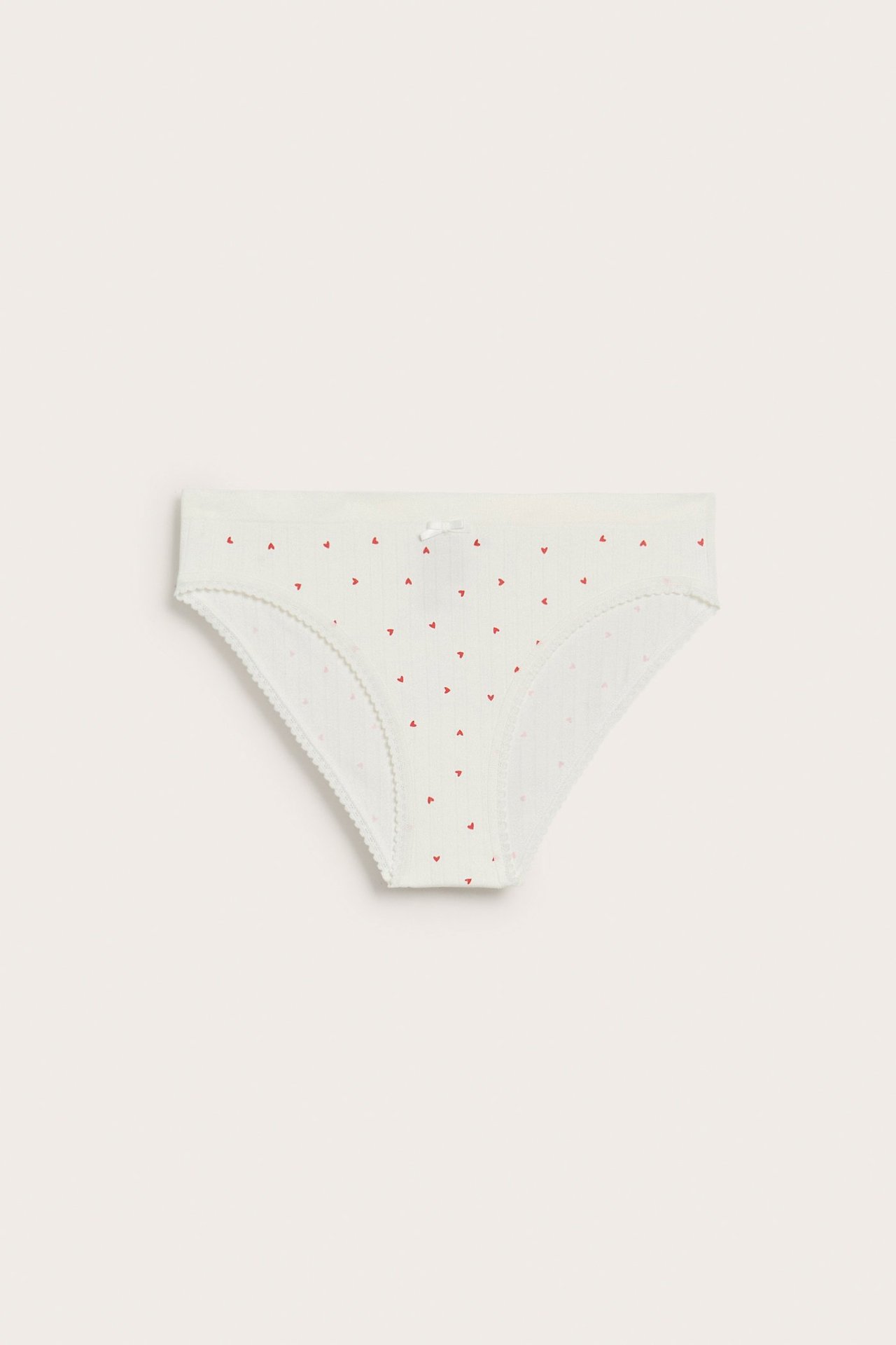 Forfra: Offwhite sømløs truse med rødt hjertemønster og liten hvit sløyfe.
