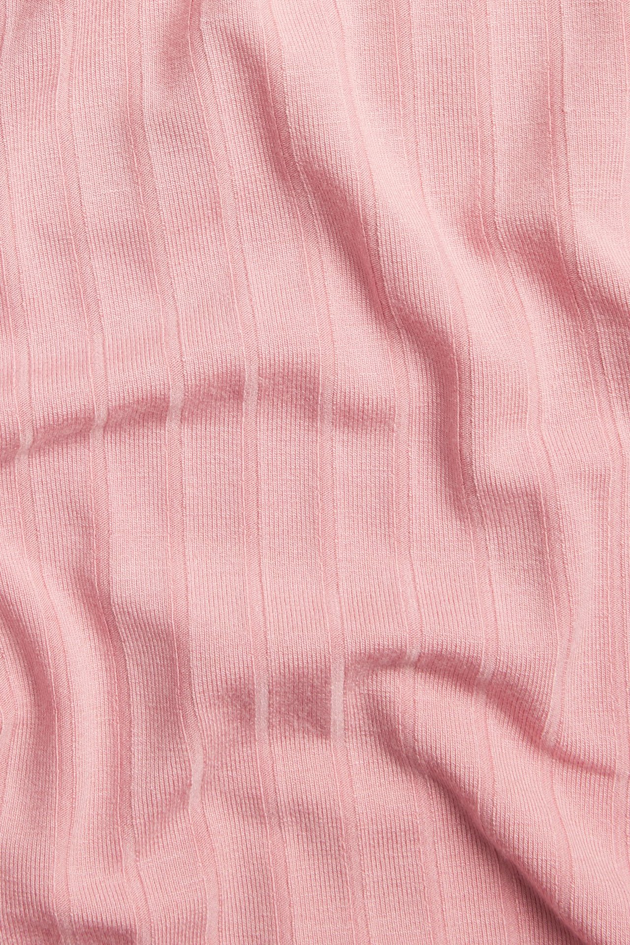 Närbild av rosa ribbat t-shirttyg, med vertikal textur.