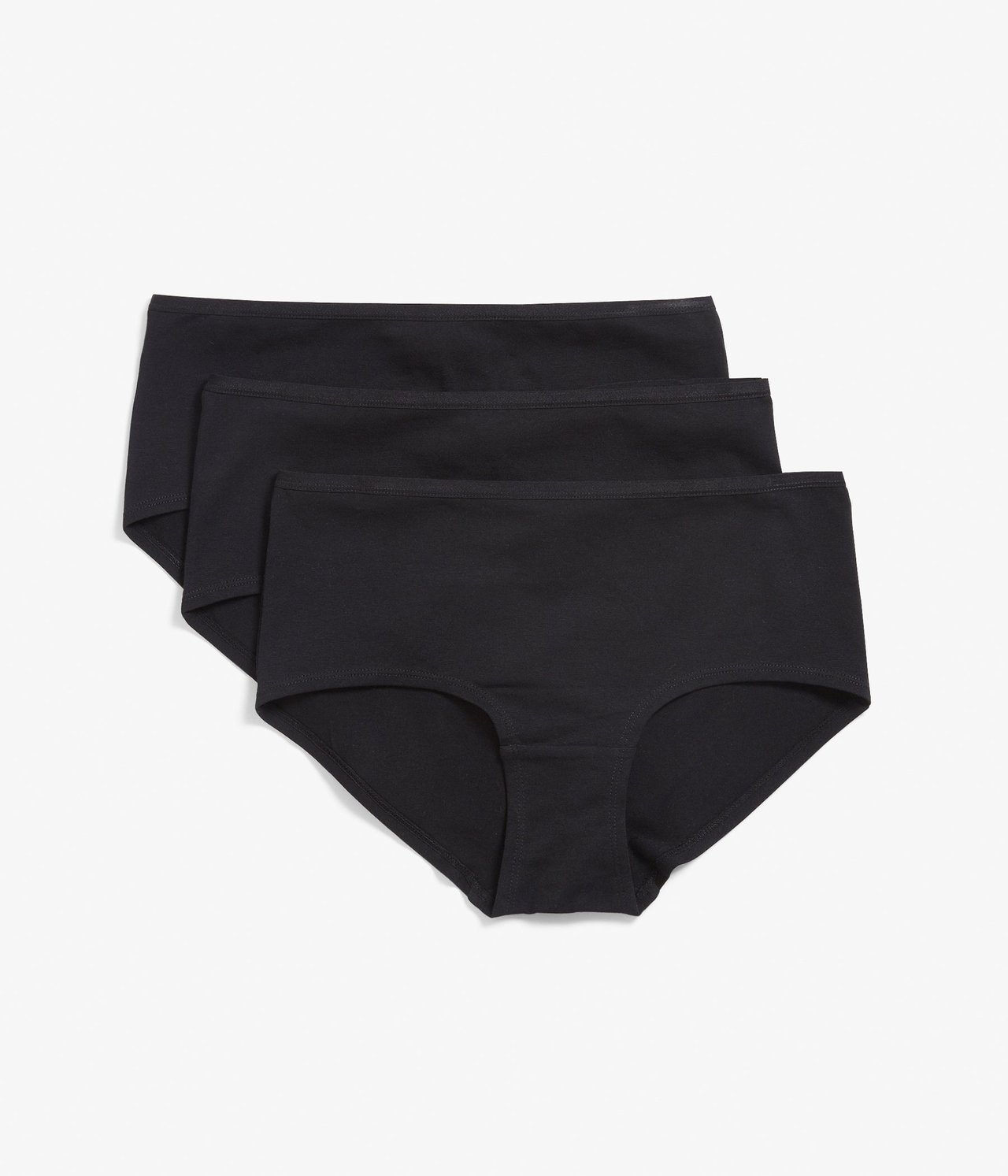 Frontvisning av tre stablede ensfargede svarte bomullshipstertruser.