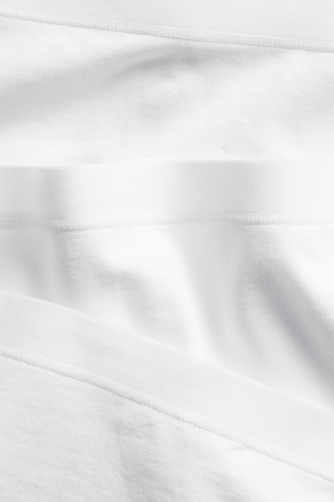 Zbliżenie białych bawełnianych bokserek z widocznymi elastycznymi pasami.