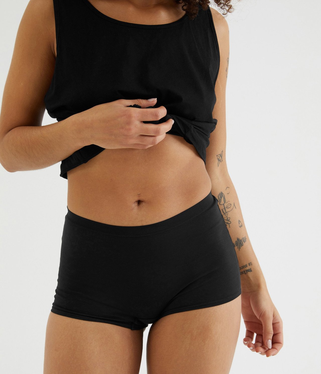 Widok z przodu kobiety w czarnych bawełnianych bokserkach i czarnym topie.