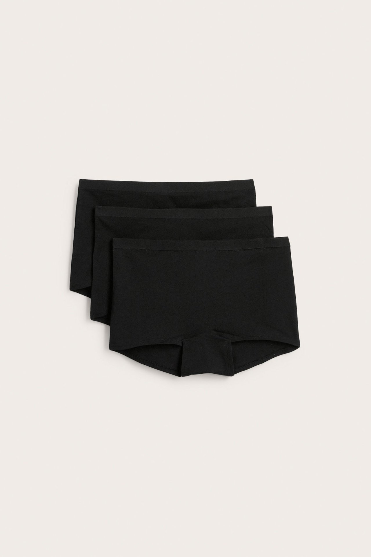 Ylhäältä: Kolme mustaa yksiväristä puuvilla-elastaani-bokserialushousua 3 kappaleen pakkauksessa, hieman päällekkäin.