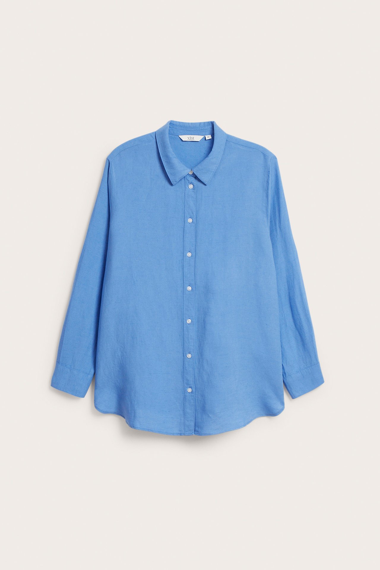 Frontvy av en klassisk blå skjorta i linnemix med långa ärmar och vita knappar framtill.