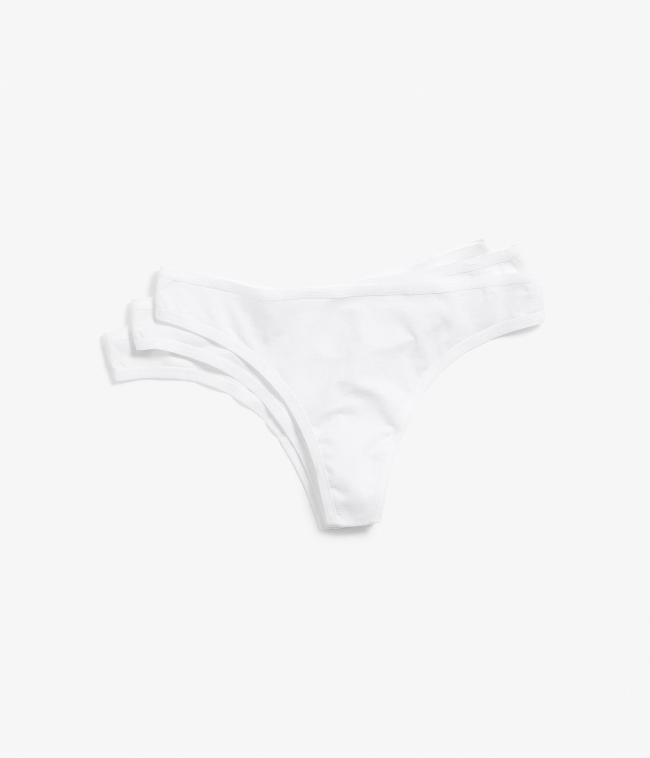 Ovenfra: Tre hvite ensfargede bomullsstringtruser ligger pent stablet.