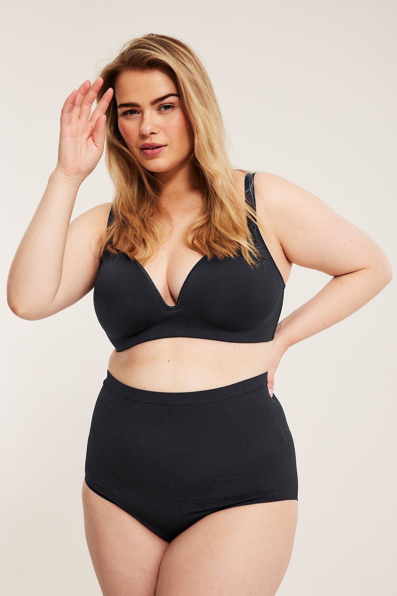 Widok z przodu kobiety w czarnym, bezszwowym biustonoszu plunge i pasujących czarnych majtkach z wysokim stanem.