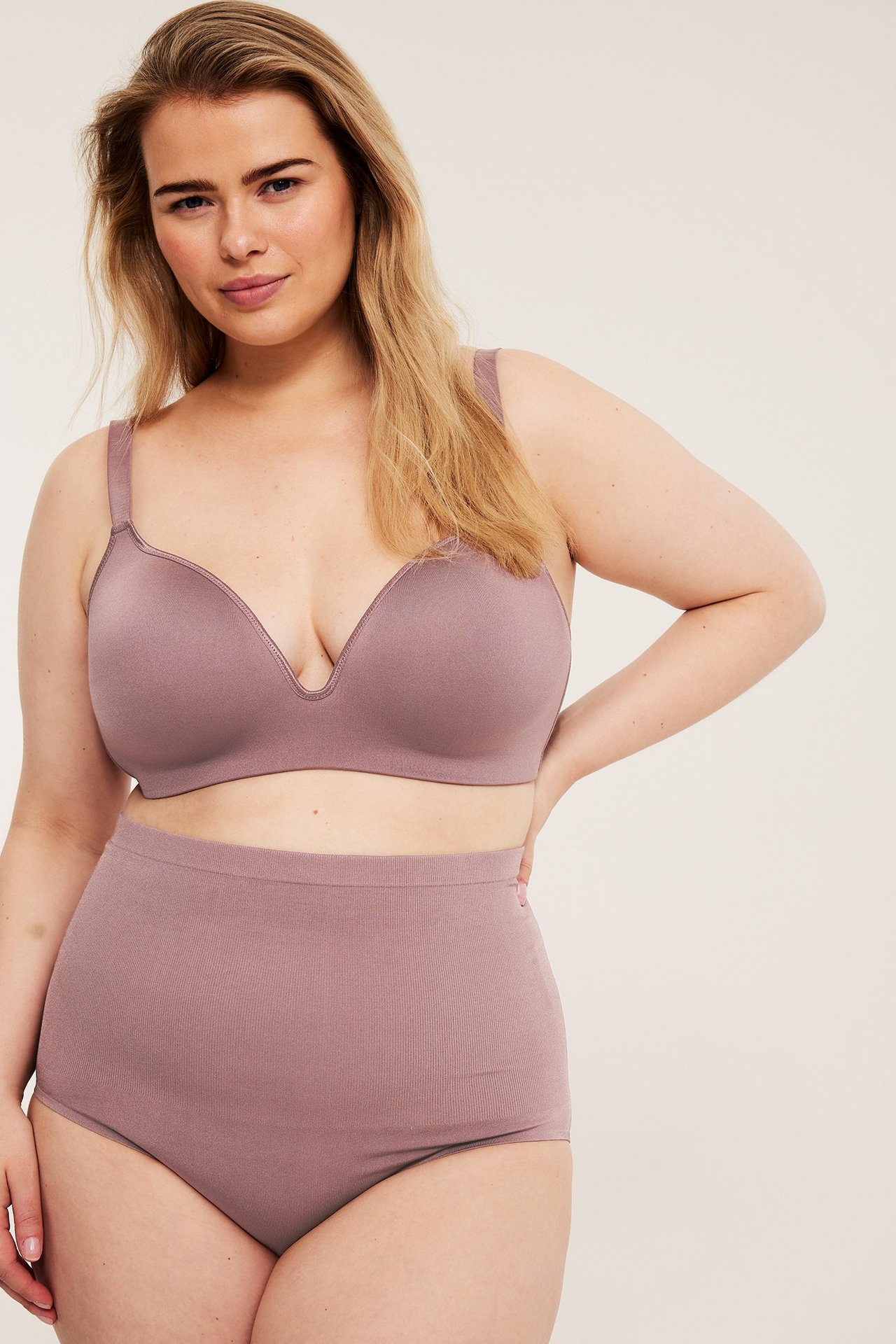Widok z przodu kobiety w ciemnoróżowym bezszwowym biustonoszu i majtkach z wysokim stanem.