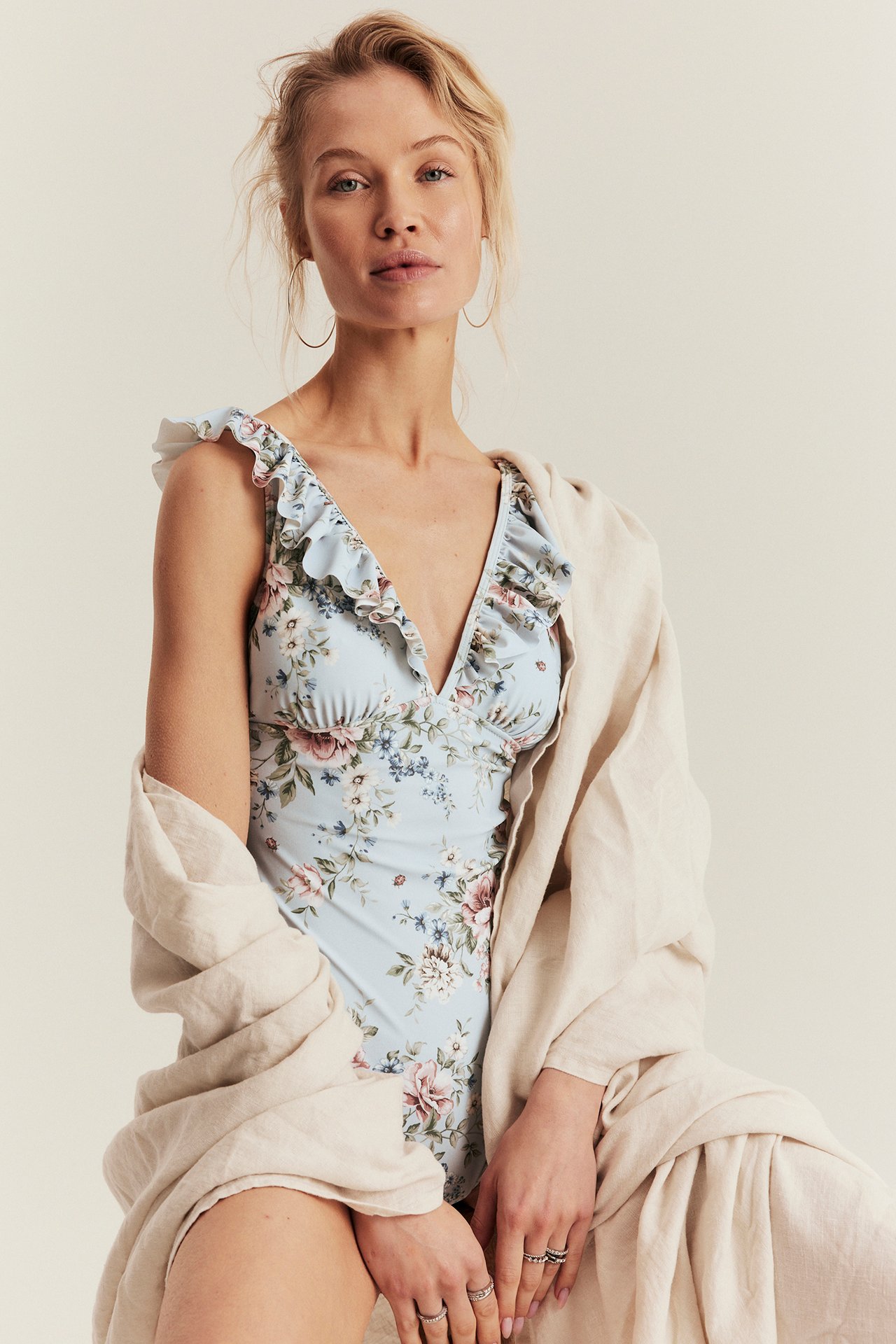 Framifrån, kvinna i ljusblå blommig baddräkt med volanger, draperad med beige linningssjal.