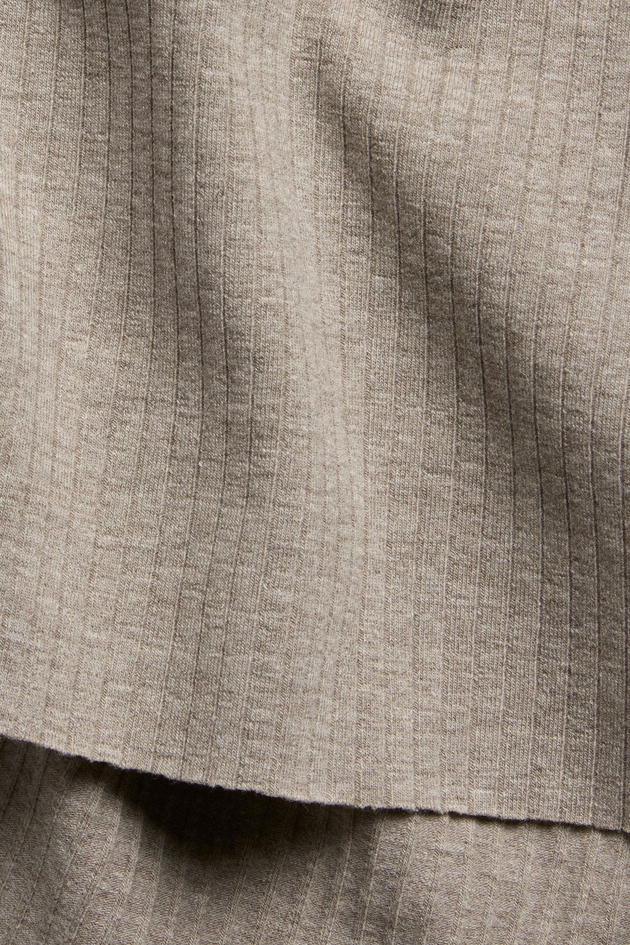 Zbliżenie na brązowo-melanżowy, prążkowany materiał topu z surowymi brzegami.