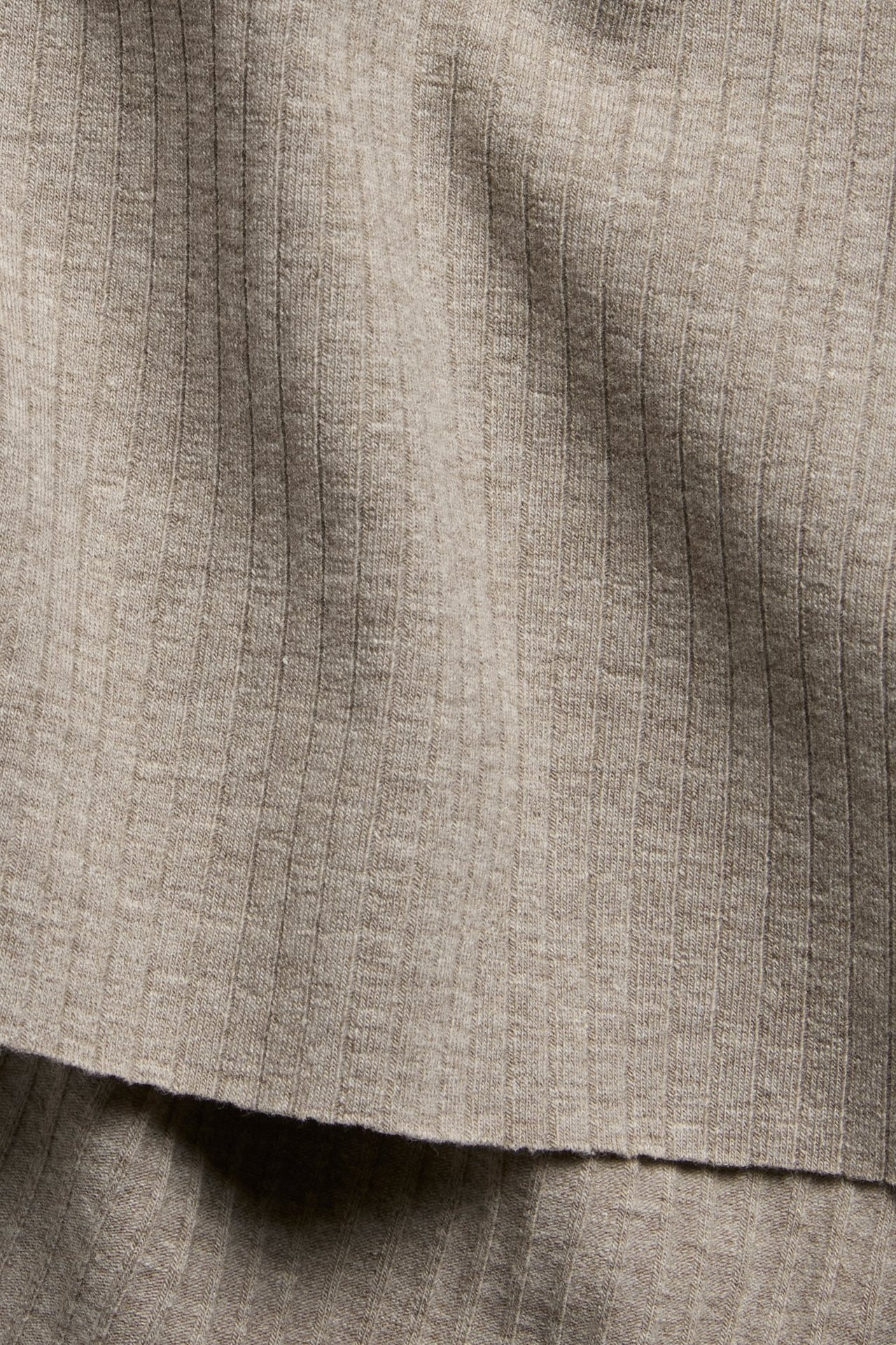 Zbliżenie na brązowo-melanżowy, prążkowany materiał topu z surowymi brzegami.