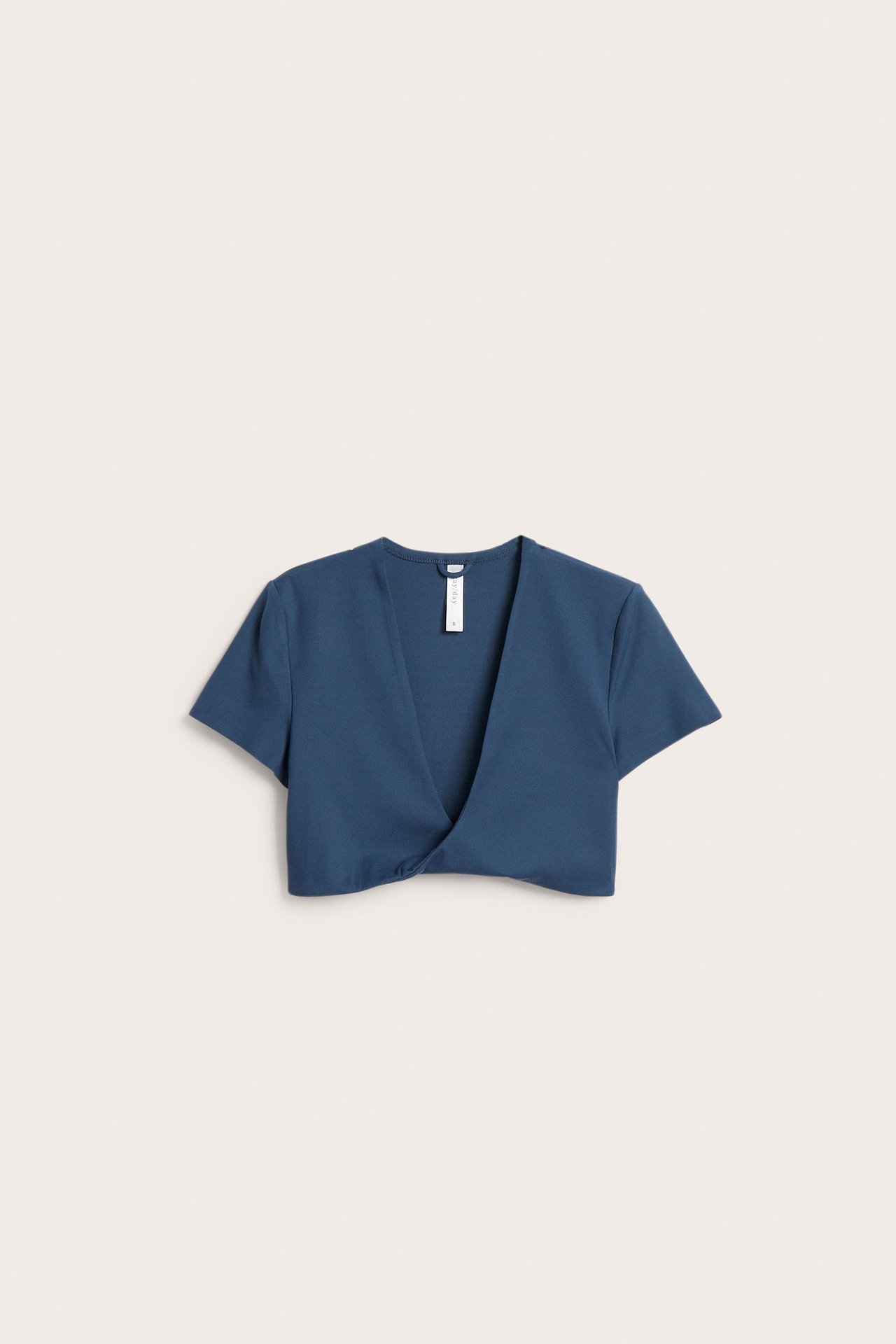 Framsida av en enfärgad blå crop top i stretchjersey med korta ärmar och vriden djup V-ringning.
