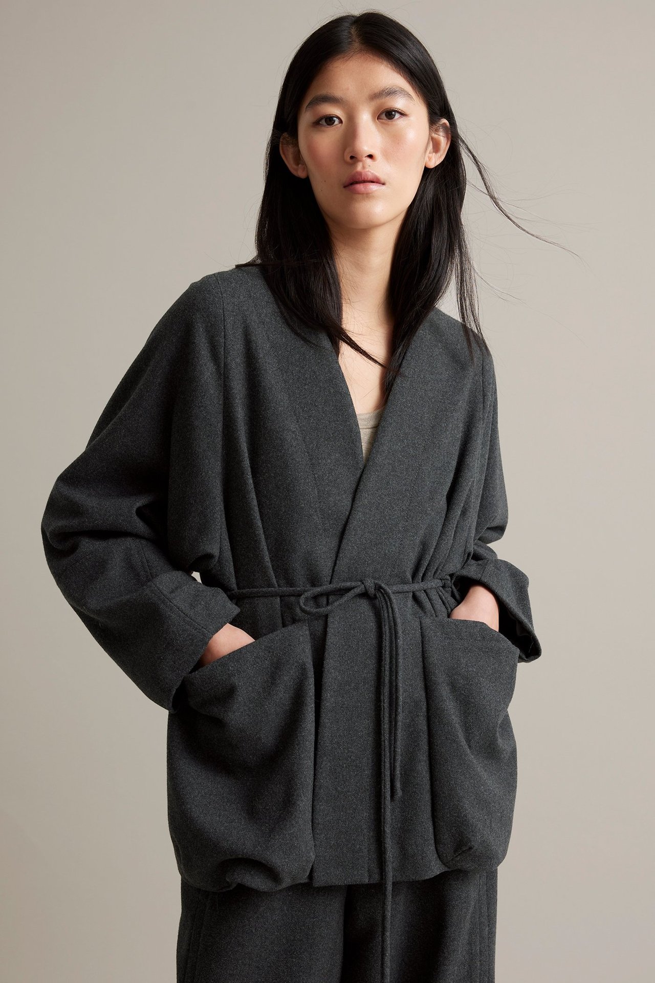 Nainen tummanharmaa villasekoite, vyöllinen, ilman kaulusta, vuorattu, etunäkymä.