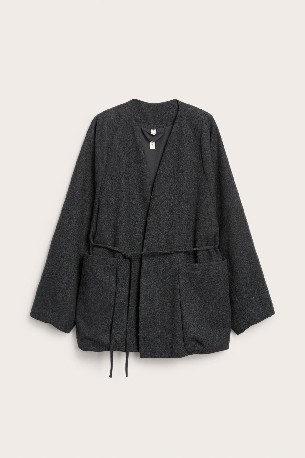 Edestä näkymä tummanharmaasta melereeratusta villasekoitetakista, jossa vyö ja kaksi etutaskua.