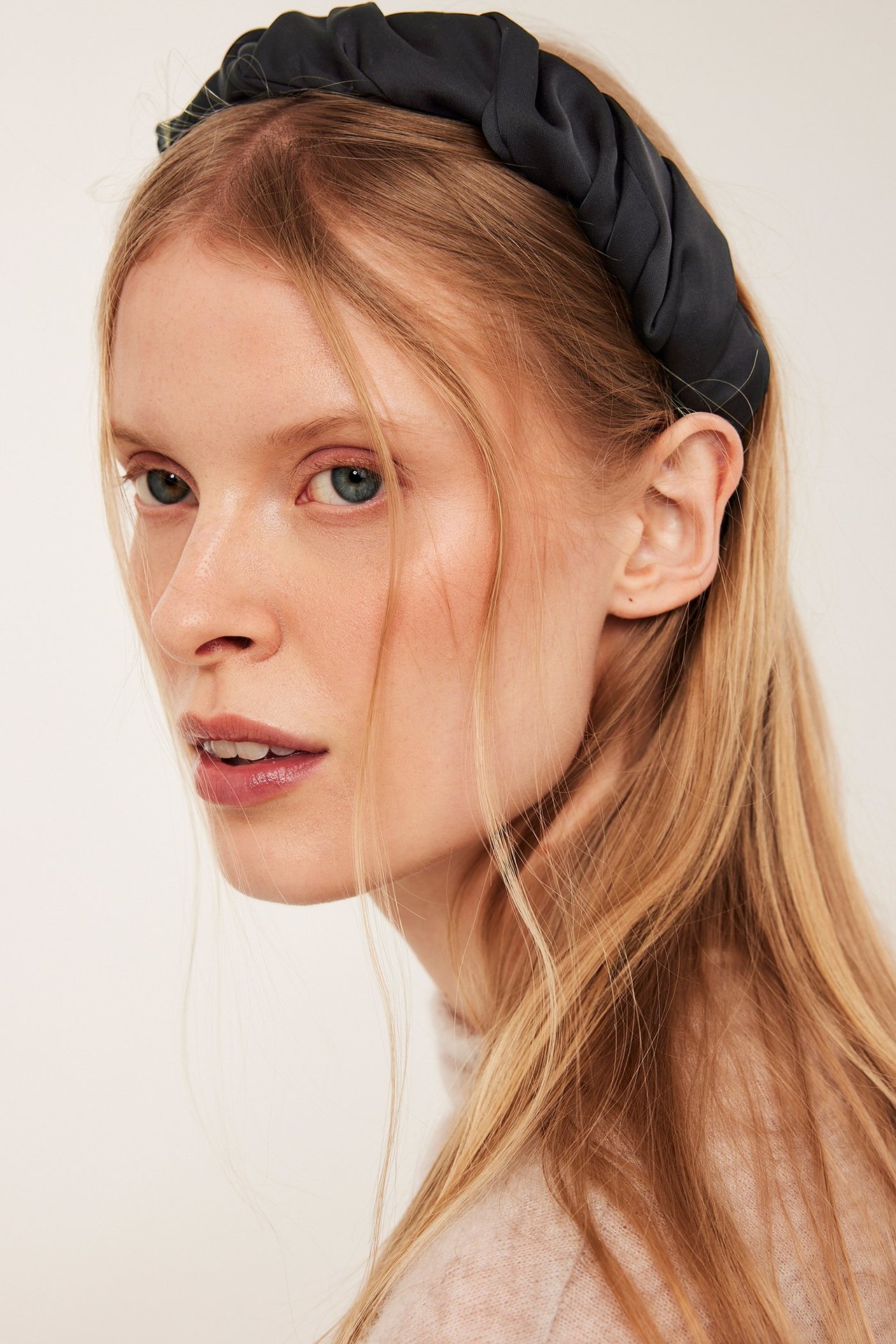 Nainen pitkällä vaaleanpuhuvalla hiuksella, musta satiinisolution sivukuva.