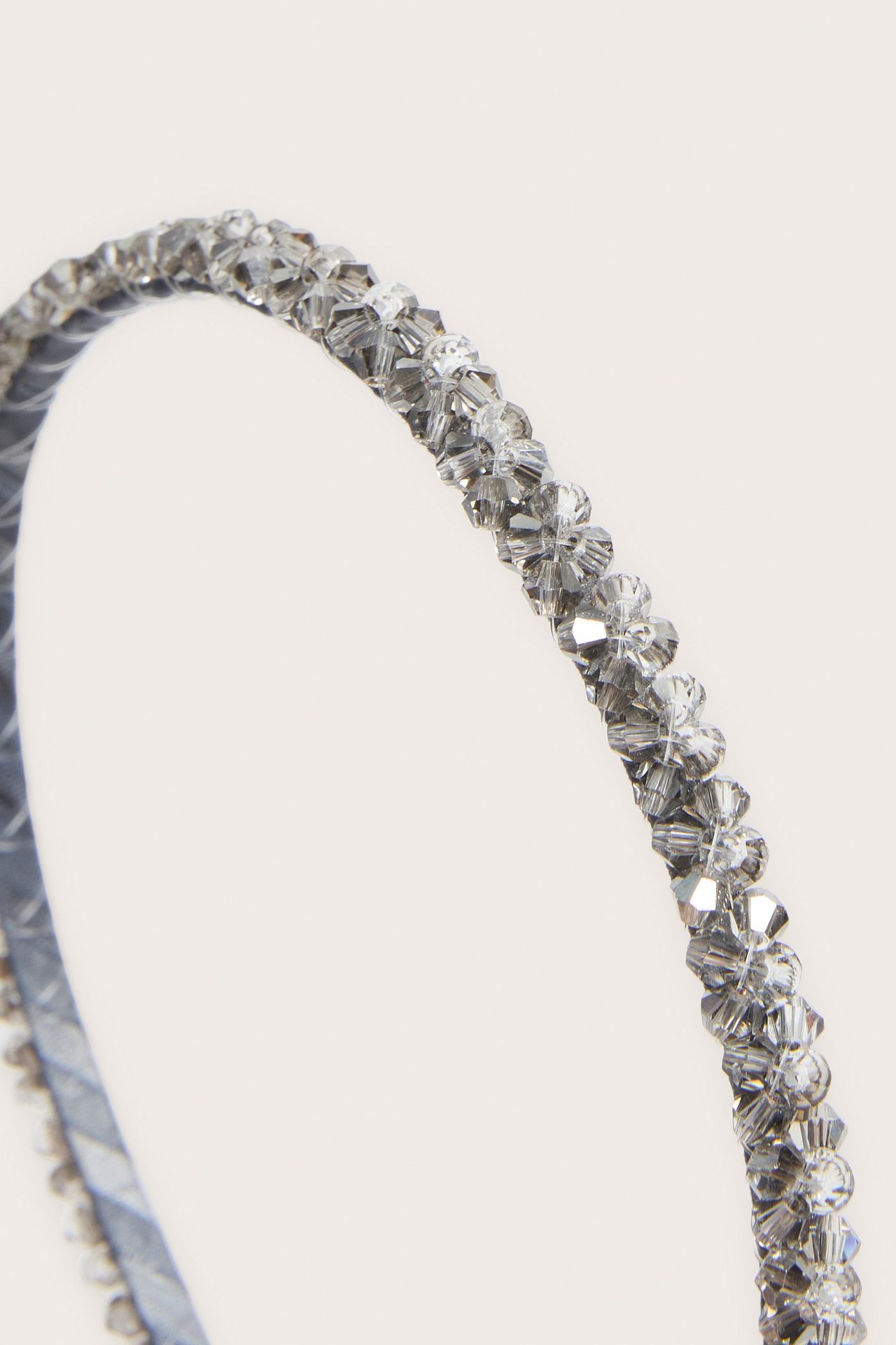 Närbild av ett silverfärgat diadem dekorerat med små, fasetterade, strassliknande pärlor.