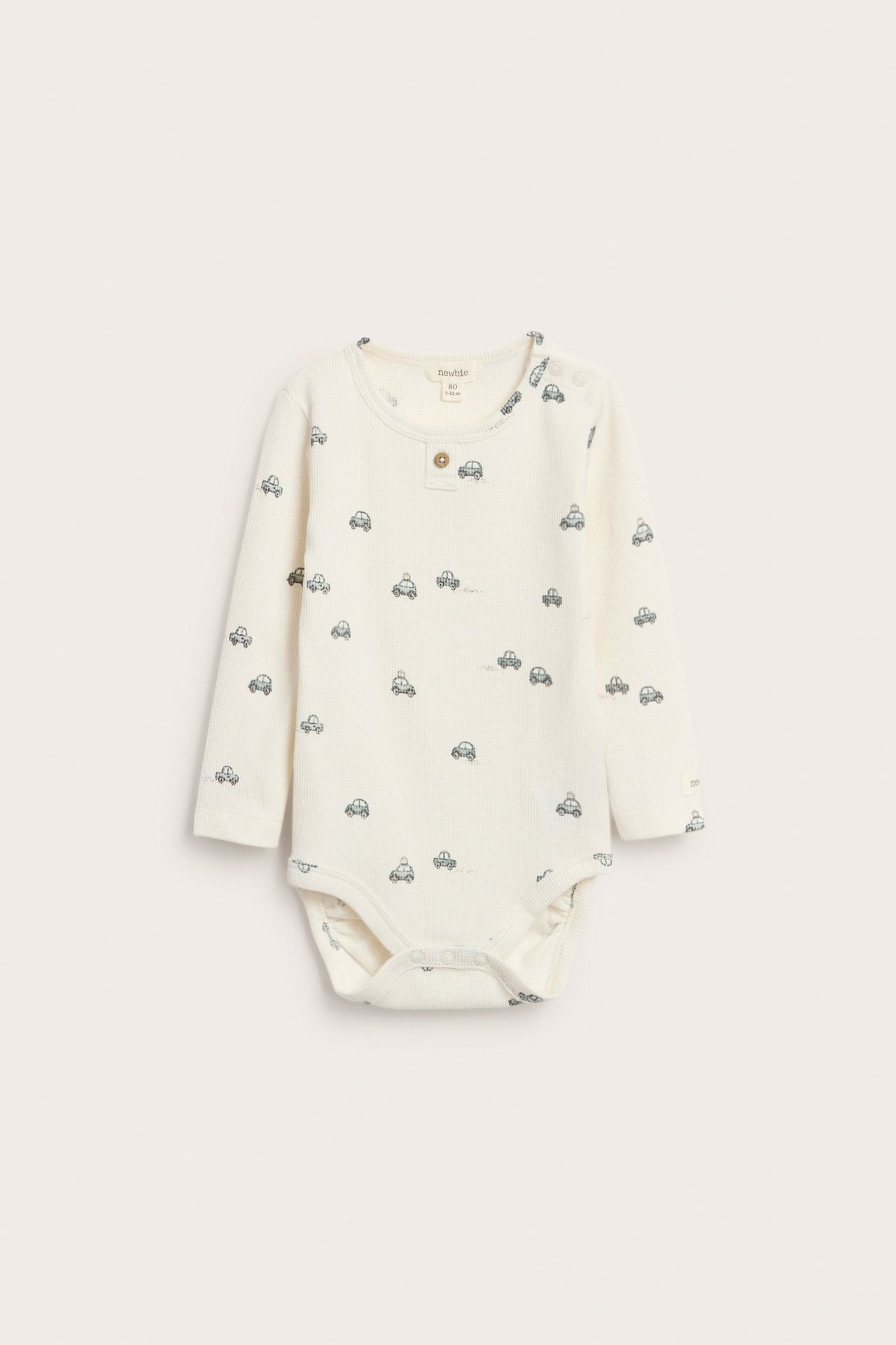 Offwhite langermet body med bilmotiv, dekorative knapper foran, trykknapper i skrittet.