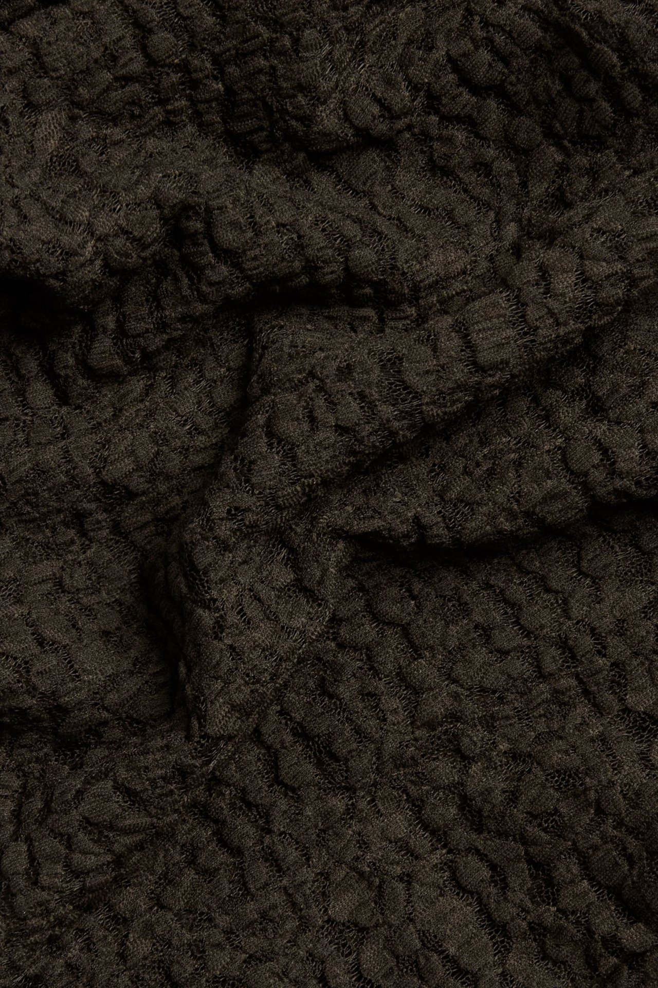 Zbliżenie na ciemnobrązową koronkową tkaninę z teksturowanym wzorem.